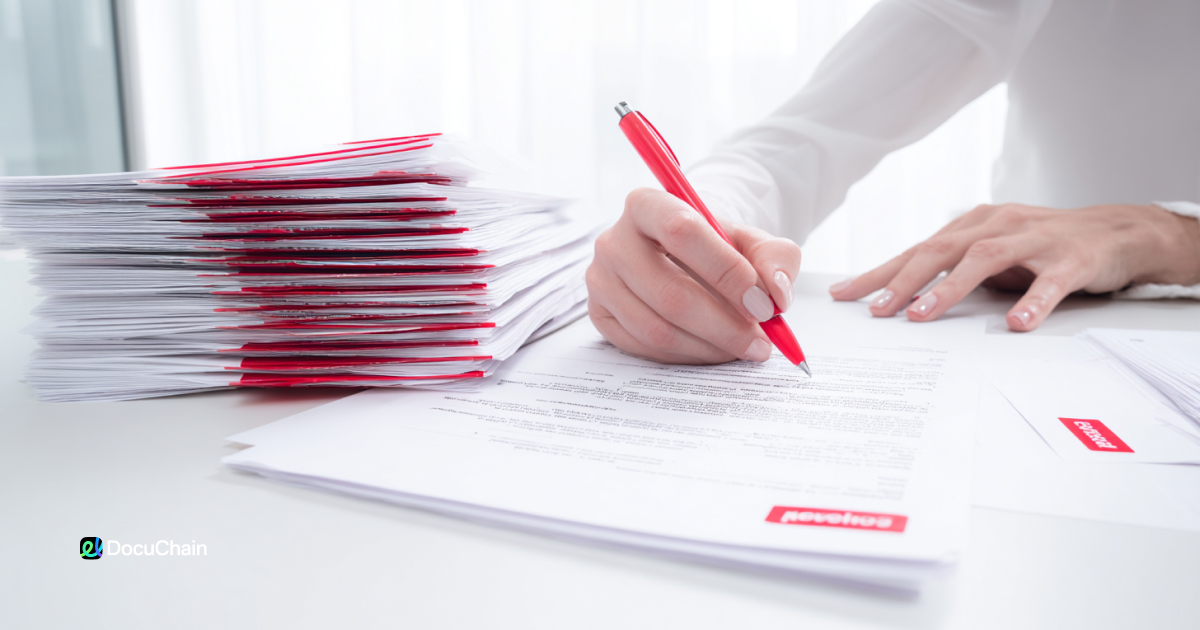 Woman signs thick stack of printed contracts manually, illustrating how digital onboarding with DocuChain can save time and reduce effort
