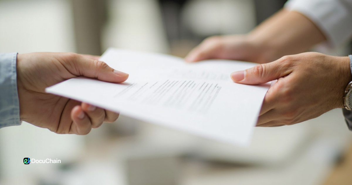 Two people exchanging a paper contract document in a business setting, close-up of hands, representing contract signing process