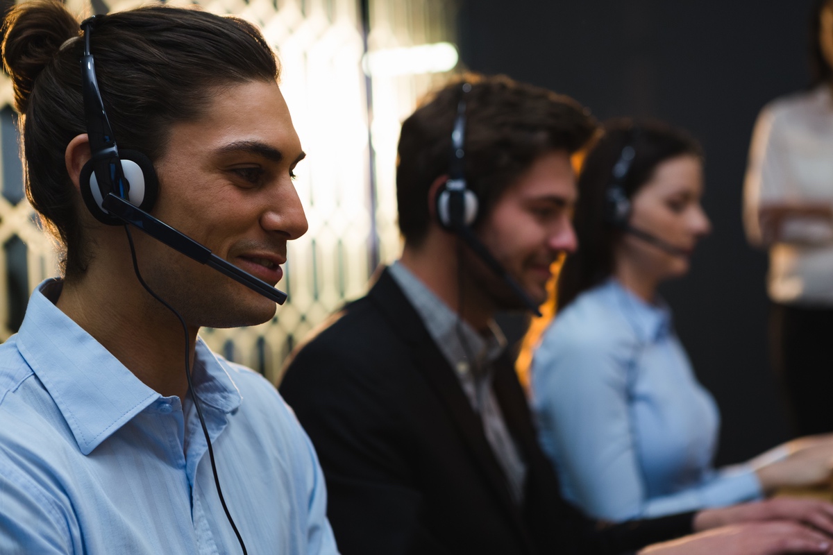 Enterprise sales team using headsets to place calls to contacts after verifying CNAM data and safeguarding number reputation with ARMOR