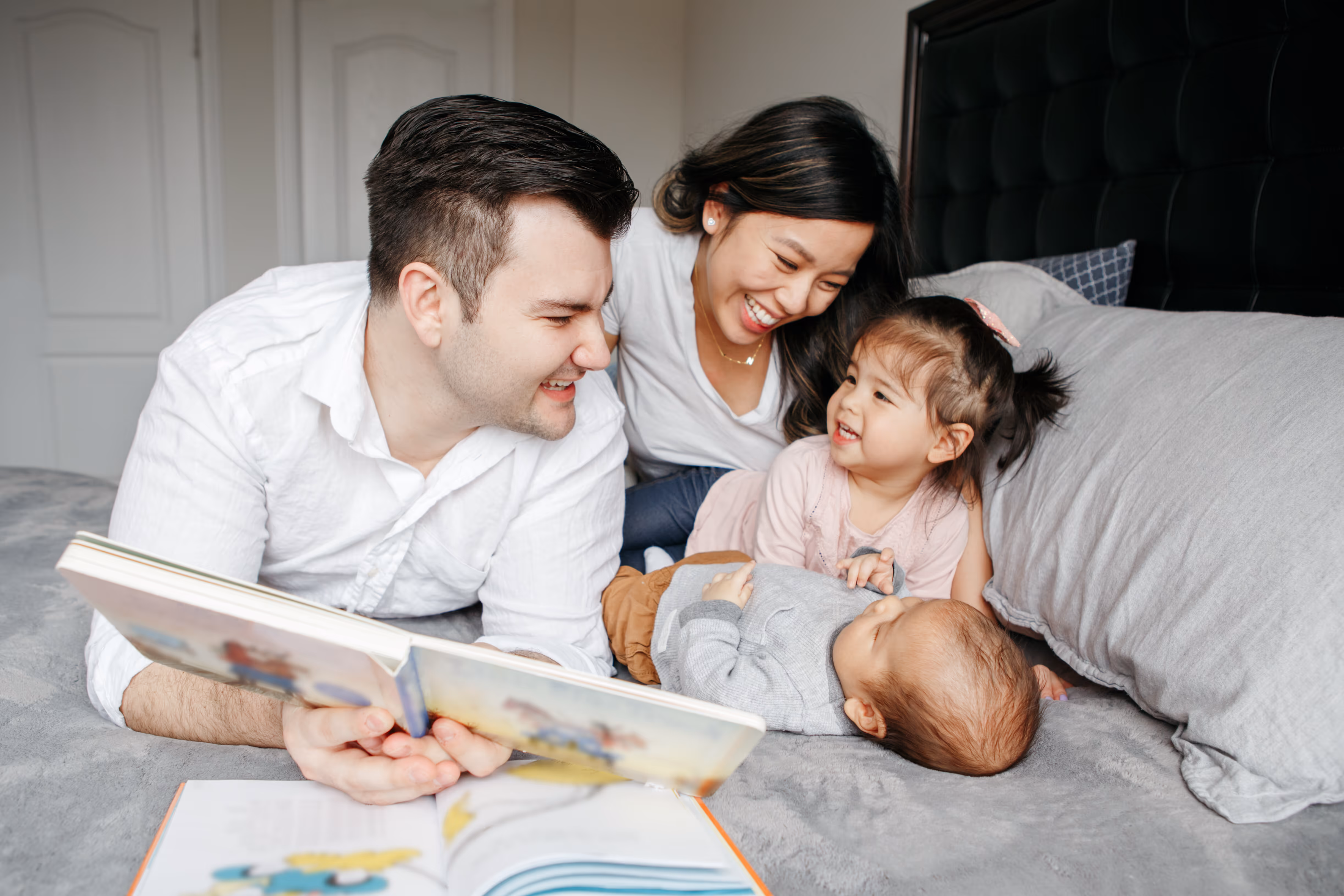 family laying on bed laughing stock image