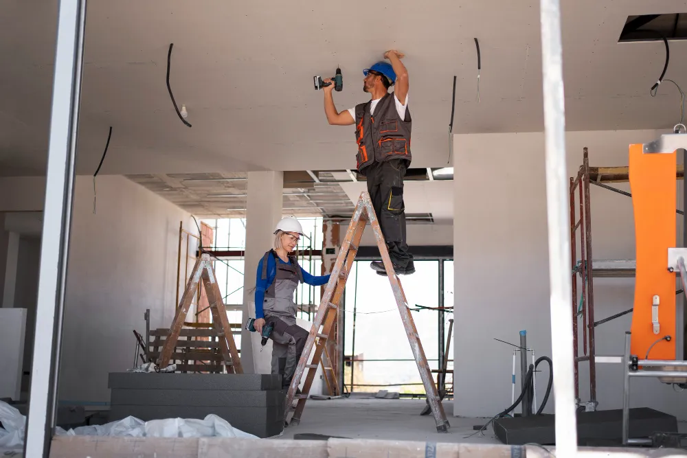A couple of men standing on top of ladders.