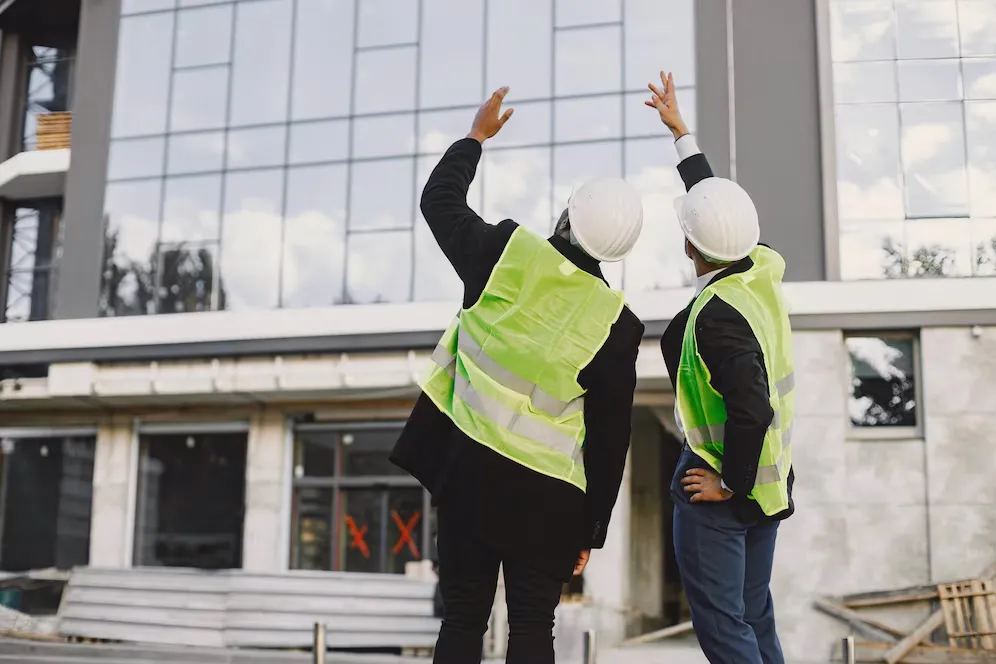 A couple of construction workers that are standing in front of a building.