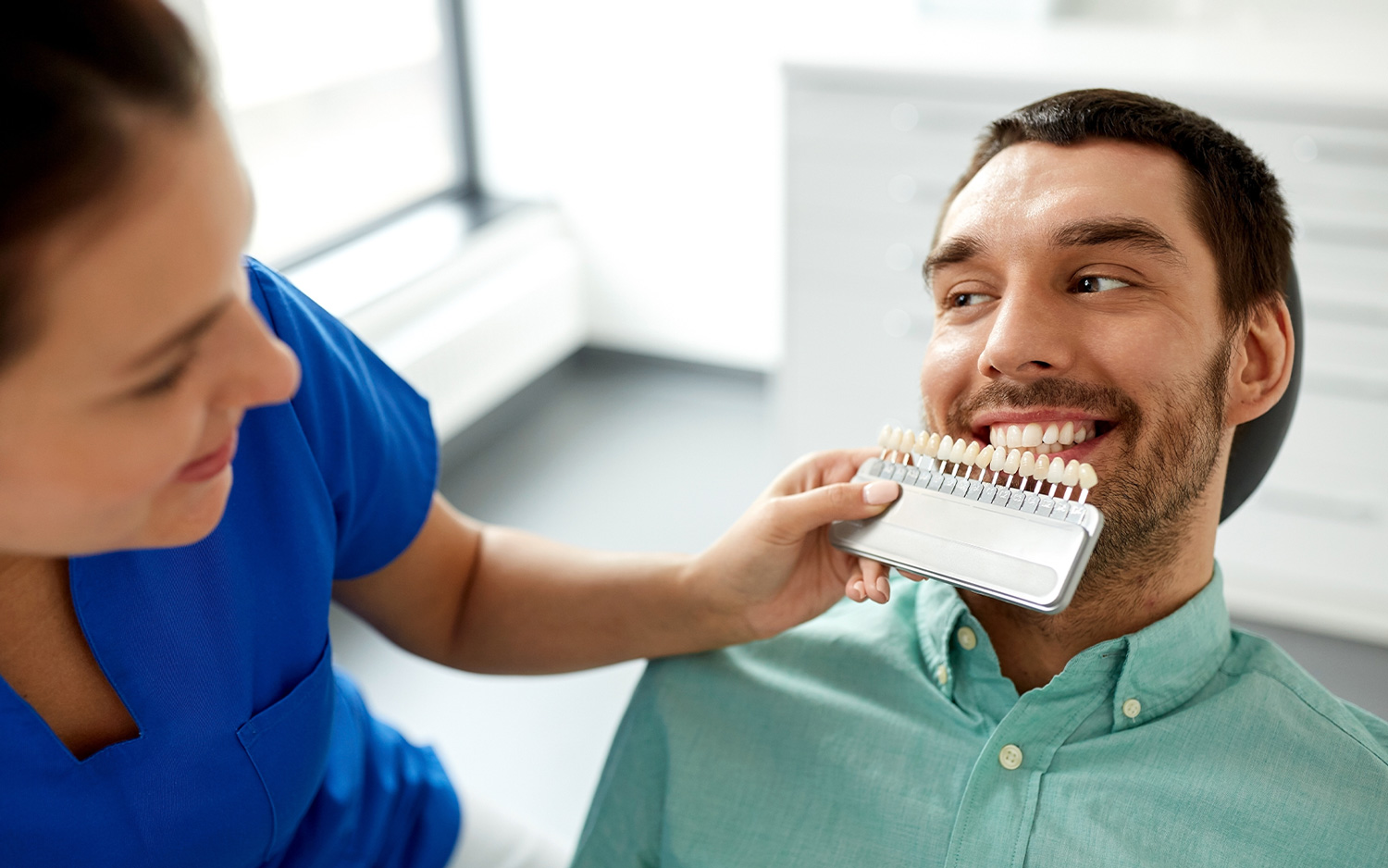 A dental assistant matches a patient’s tooth color for veneers at the best dentist in Los Gatos