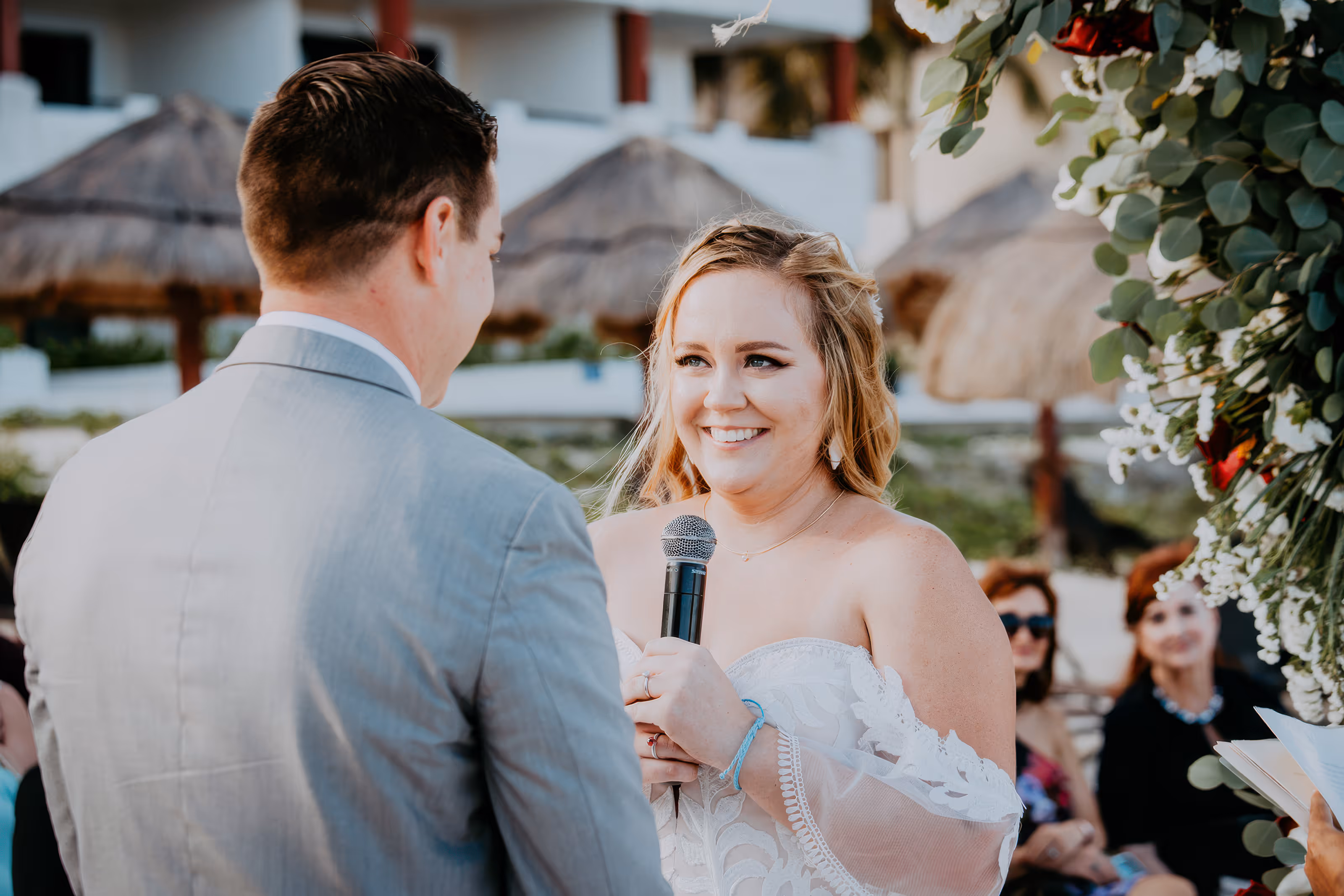 Bride smiling and holding a microphone, facing groom during an outdoor Dominican Republic destination wedding ceremony.