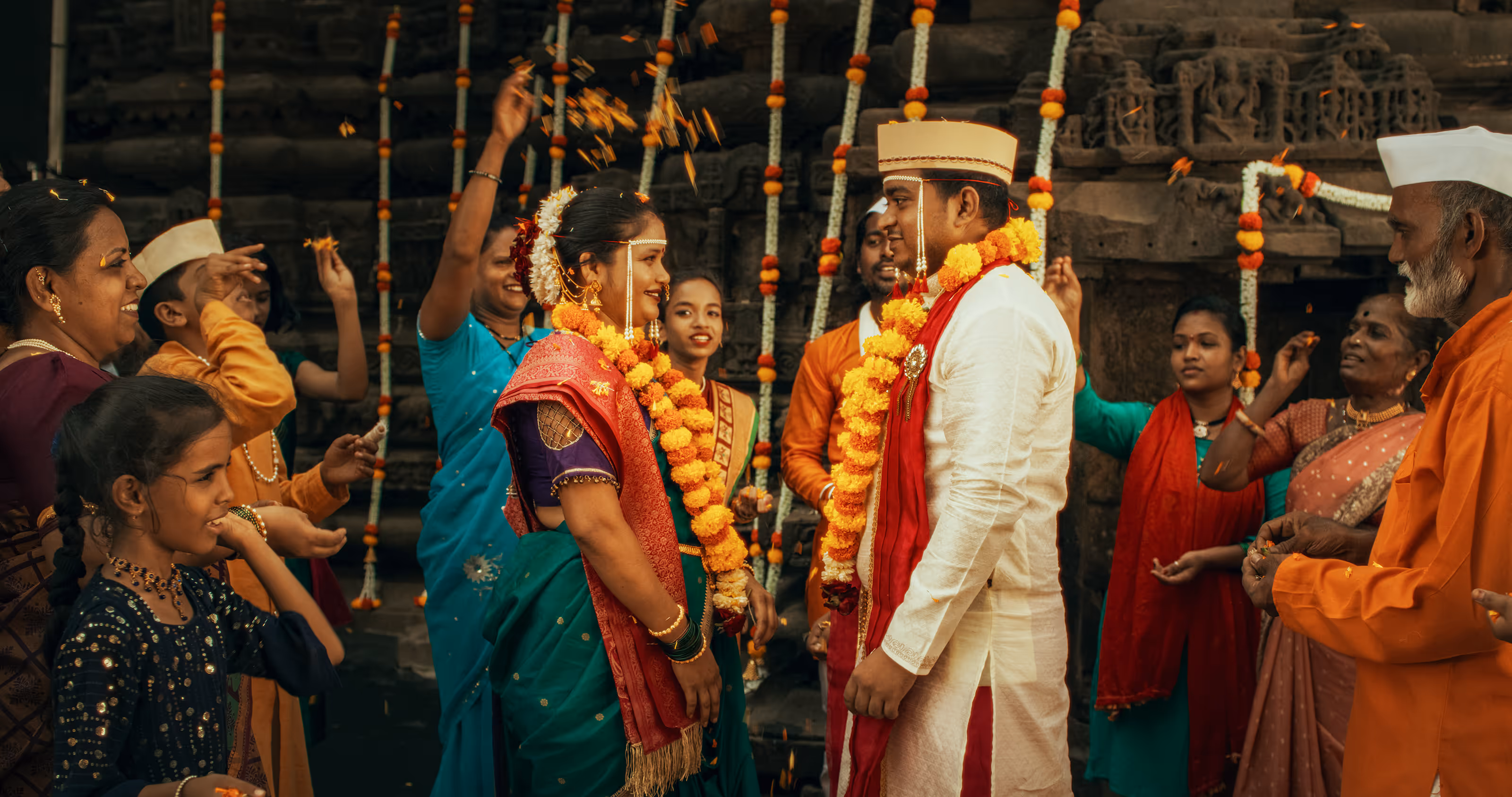 Indian bride and groom in traditional attire with flower garlands during a South Asian destination wedding ceremony.
