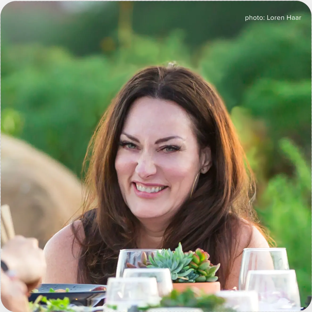 Jennifer Love. A woman smiles while seated at an outdoor table