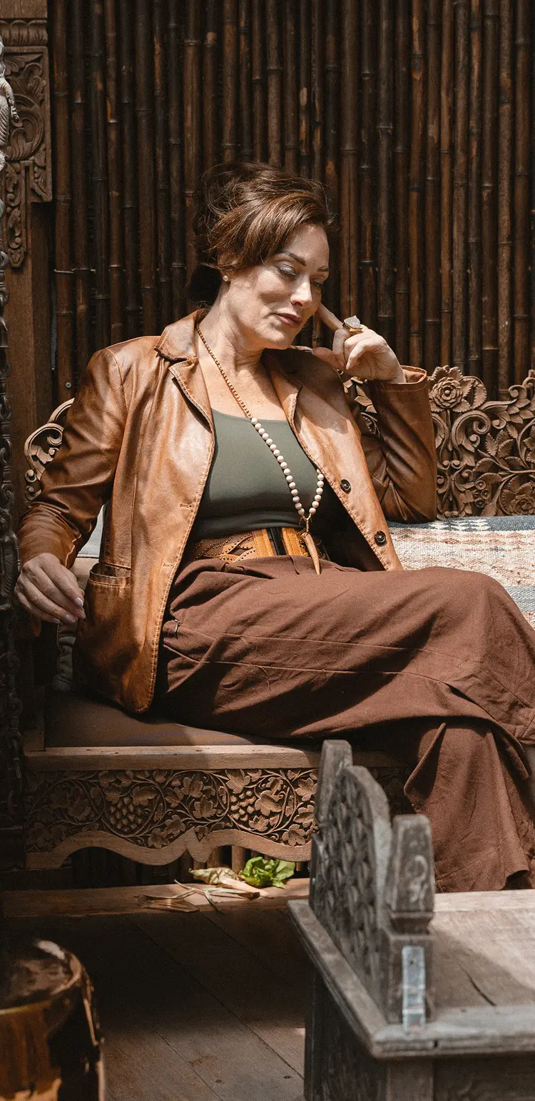 Portrait of a woman in a vibrant red robe, her dark hair framing a face looking forward, set against a subtle, decorative backdrop.