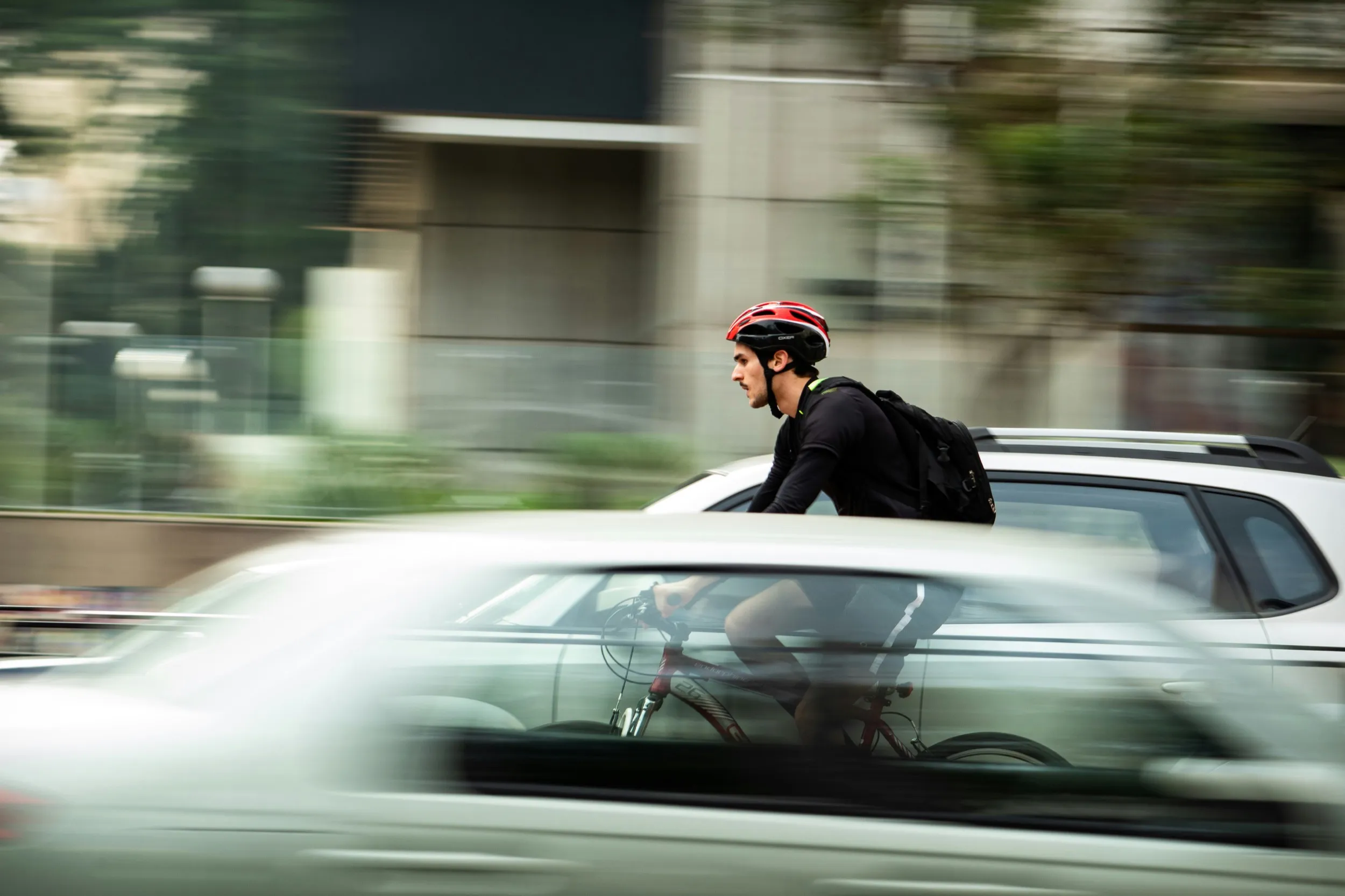 man riding a bike between cars