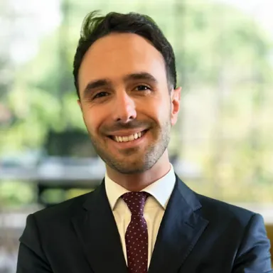 A man in a suit and tie smiling at the camera.