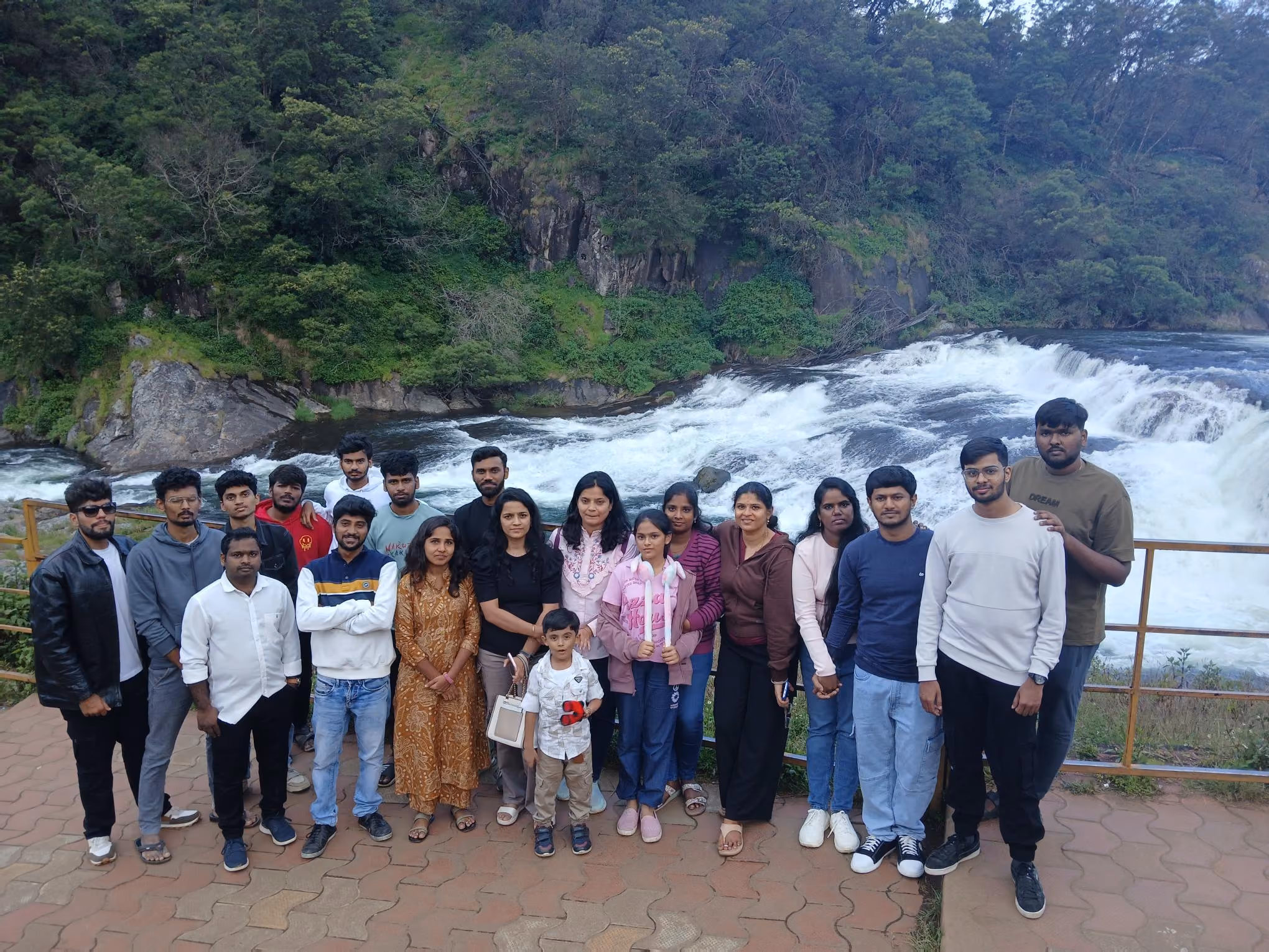 Settyl Team on a paved area with a river and waterfall surrounded by lush green trees in the background.