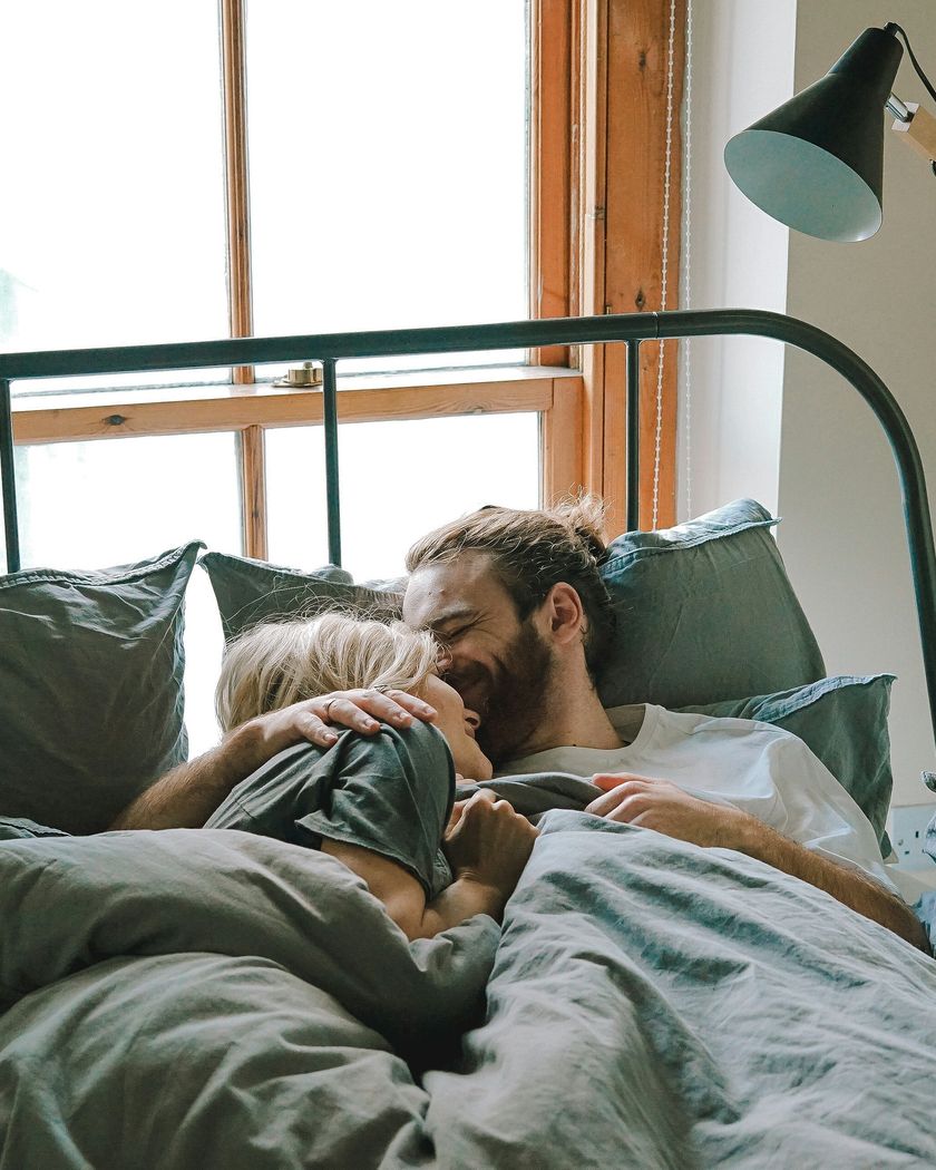 Couple laughing together in bed in soft morning light