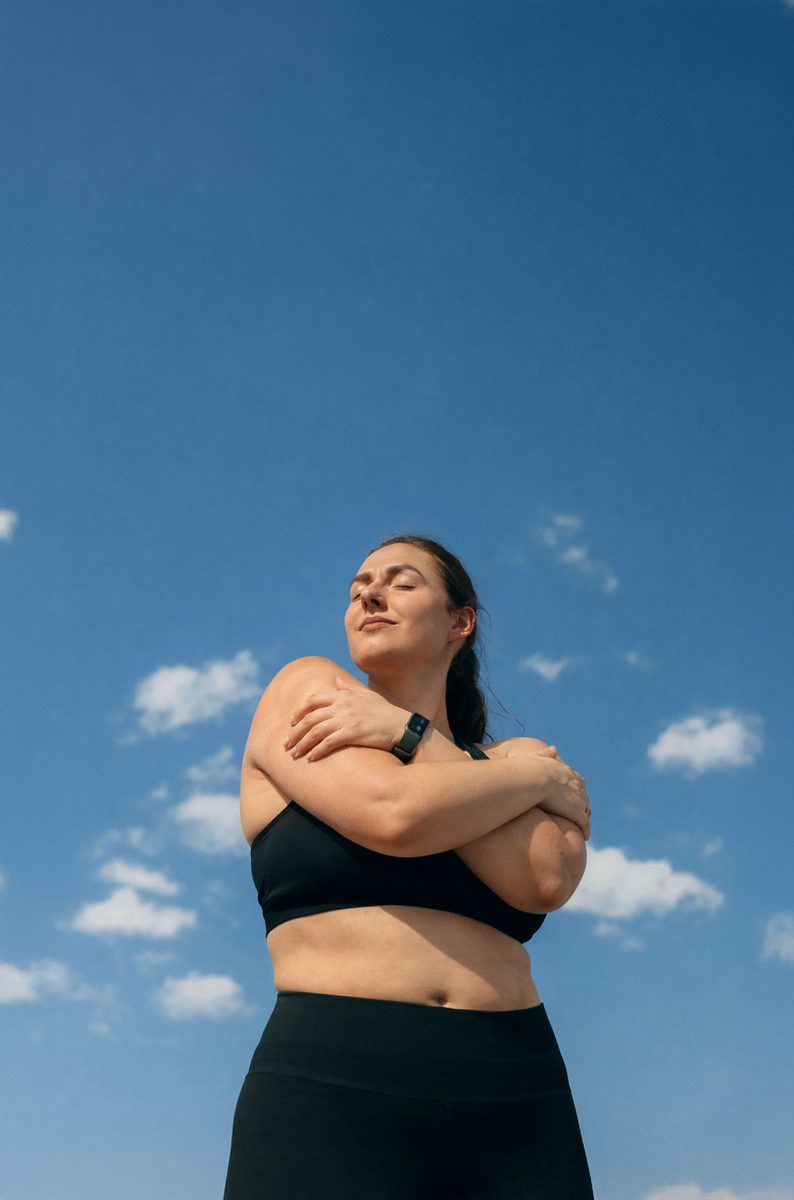 Woman hugging herself under a blue sky