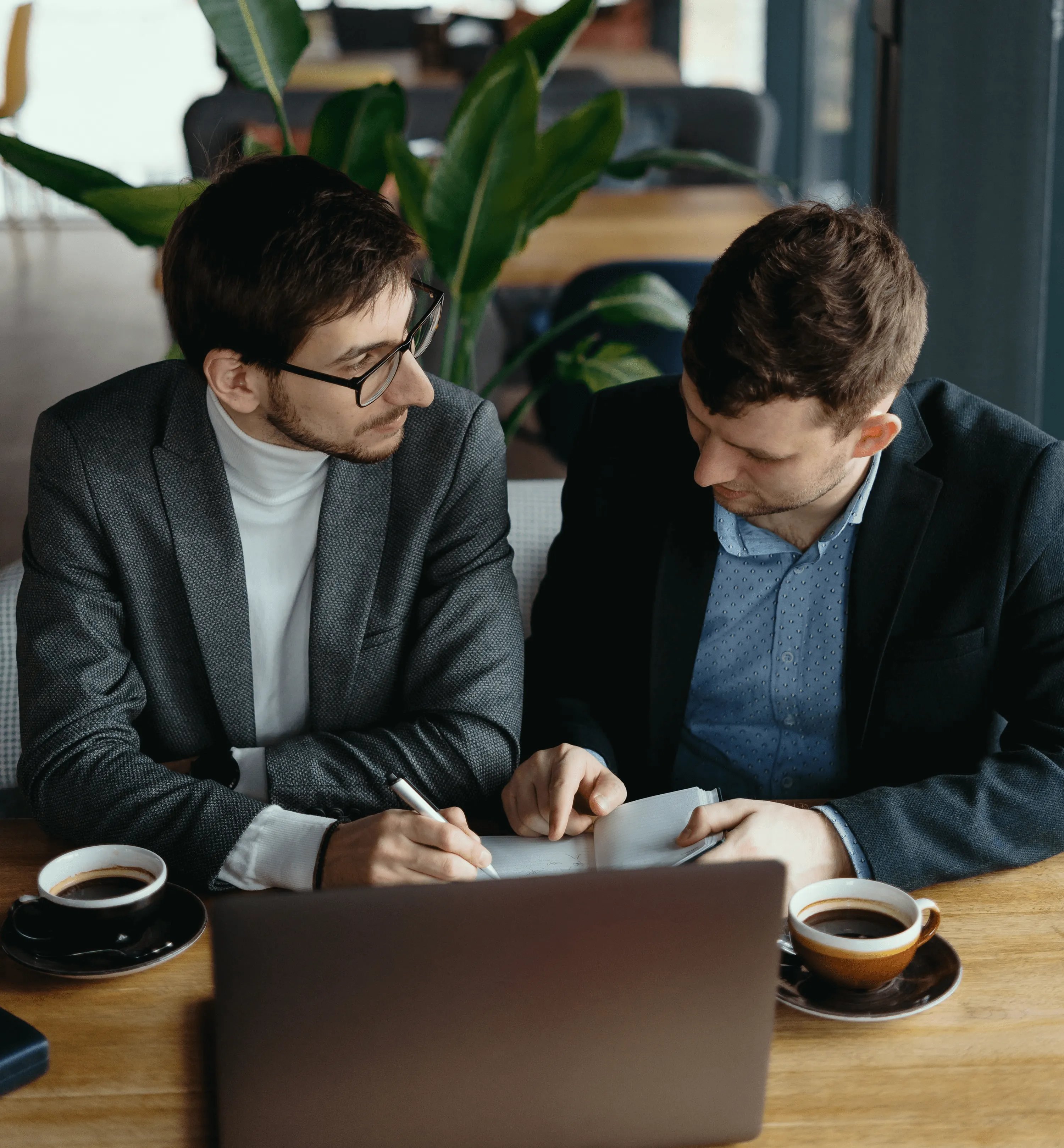 Two men having a discussion in front of a laptop