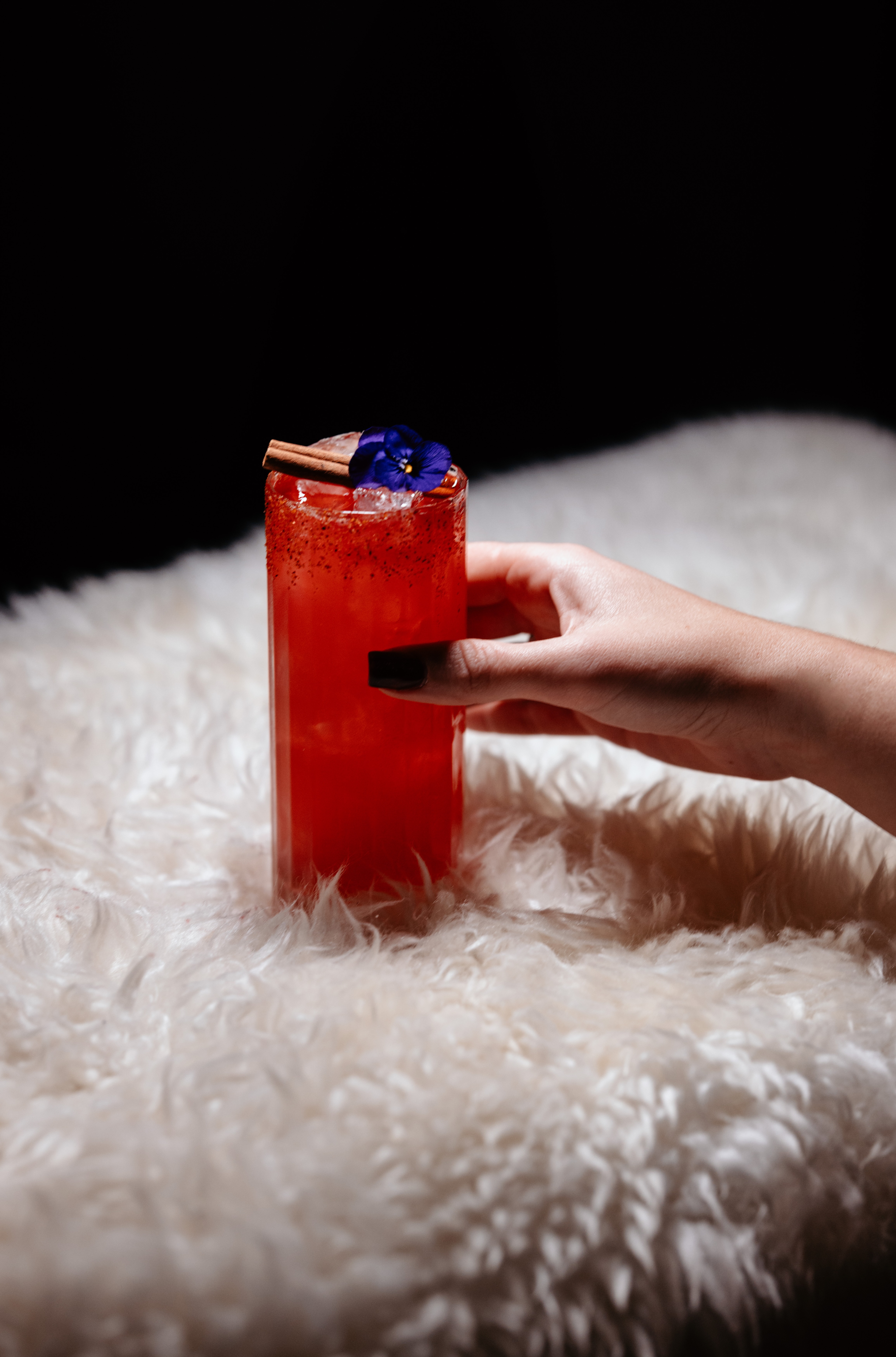 Femme tenant un cocktail rouge dans la main, sur un tapis blanc, Ferme Saint Amour Paris