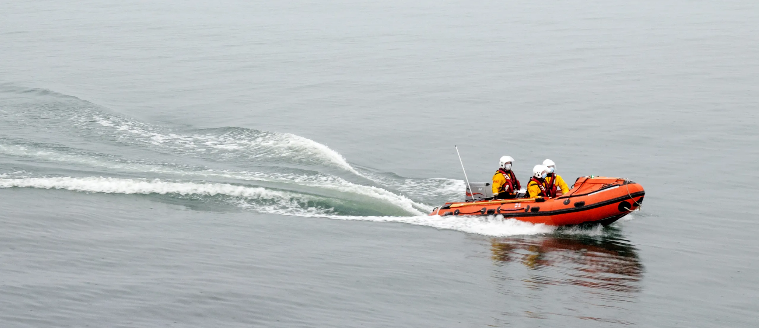 People with safety gear on a small orange boat