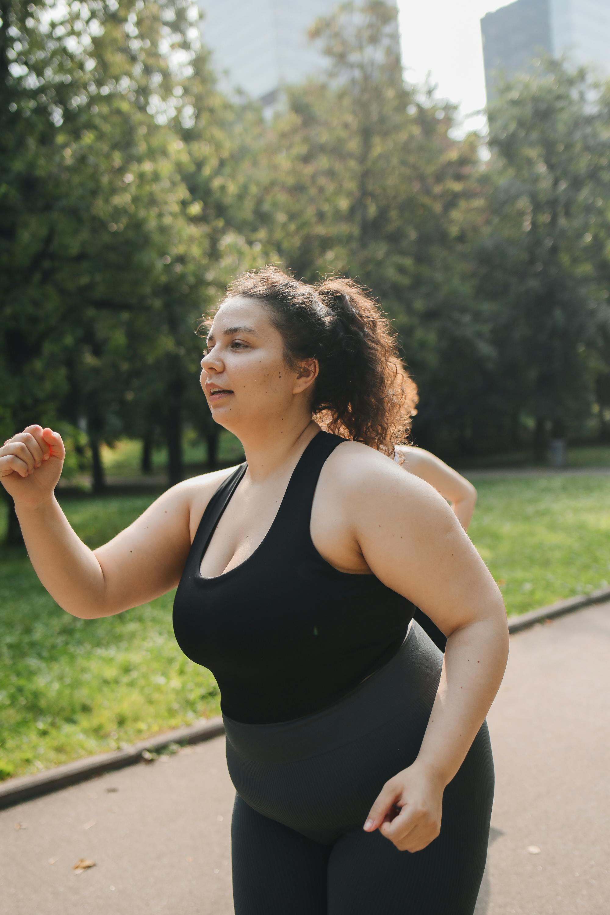 Plus size woman in workout clothes walking in a park