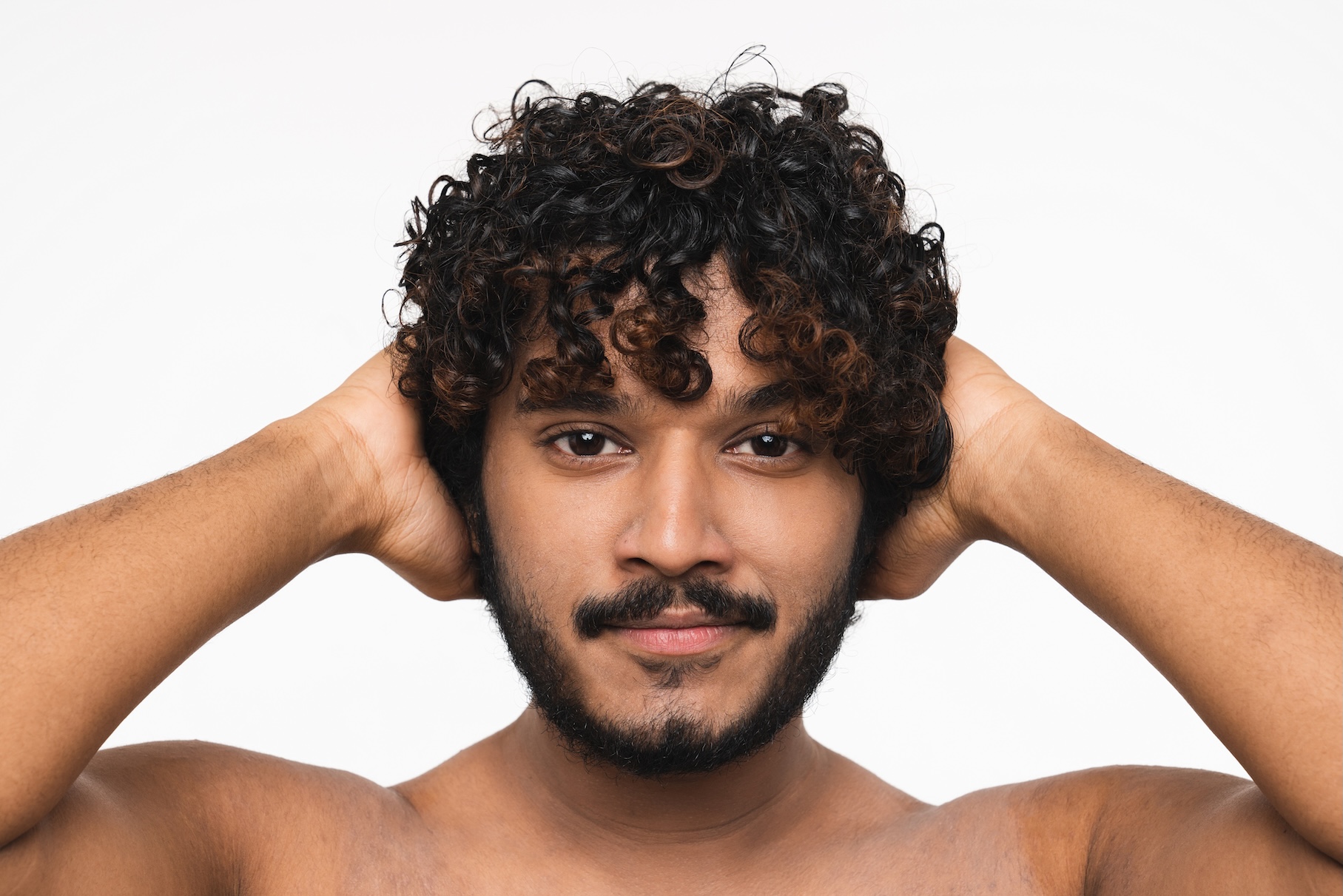 Man with dark curly hair an trimmed beard