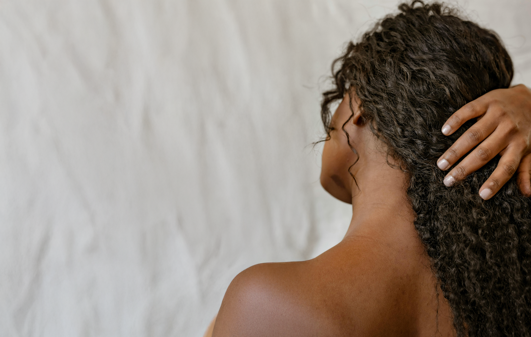 Back of woman's head featuring long, dark, curly hair