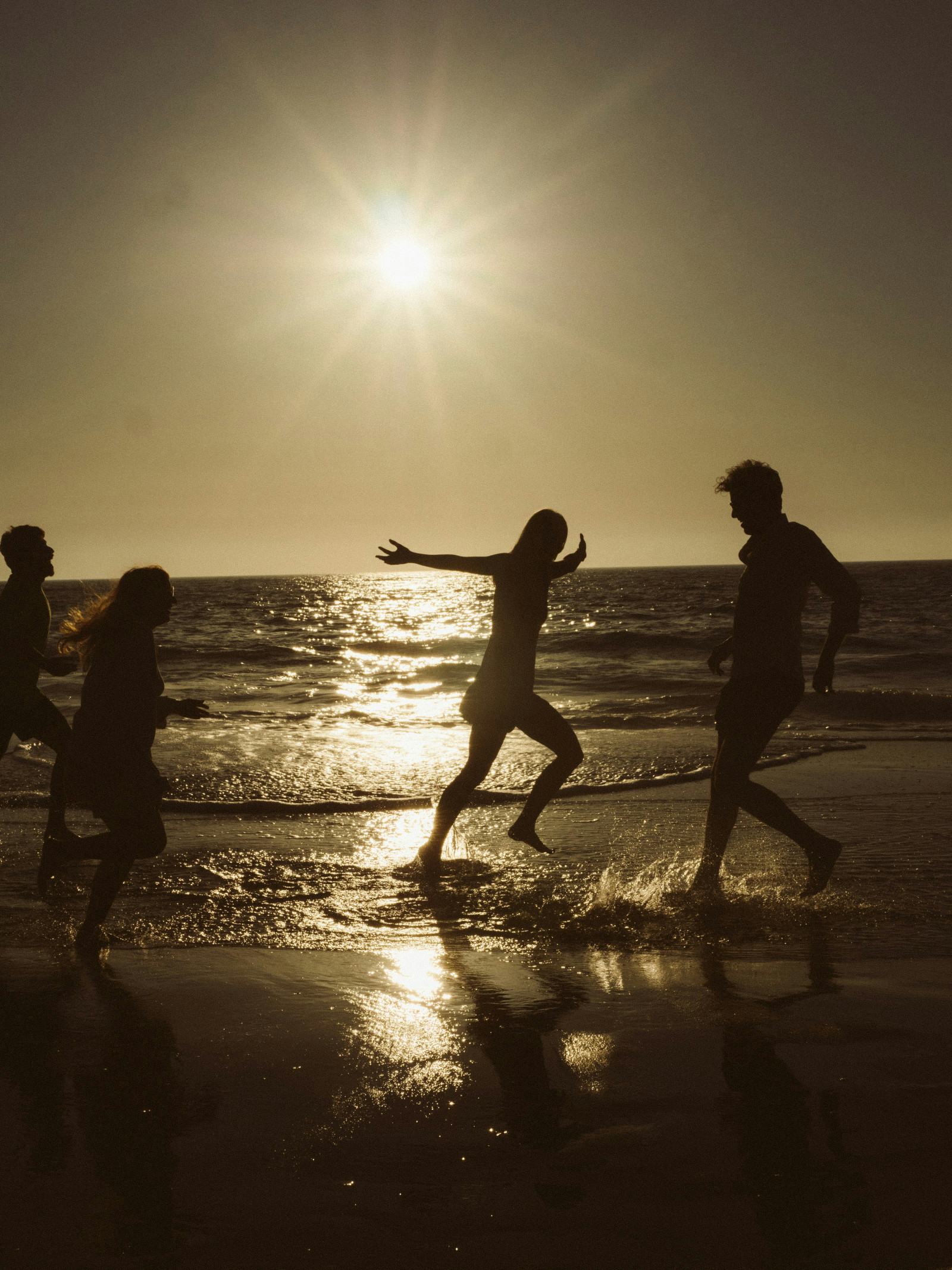 People running along the beach at sunset or sunrise