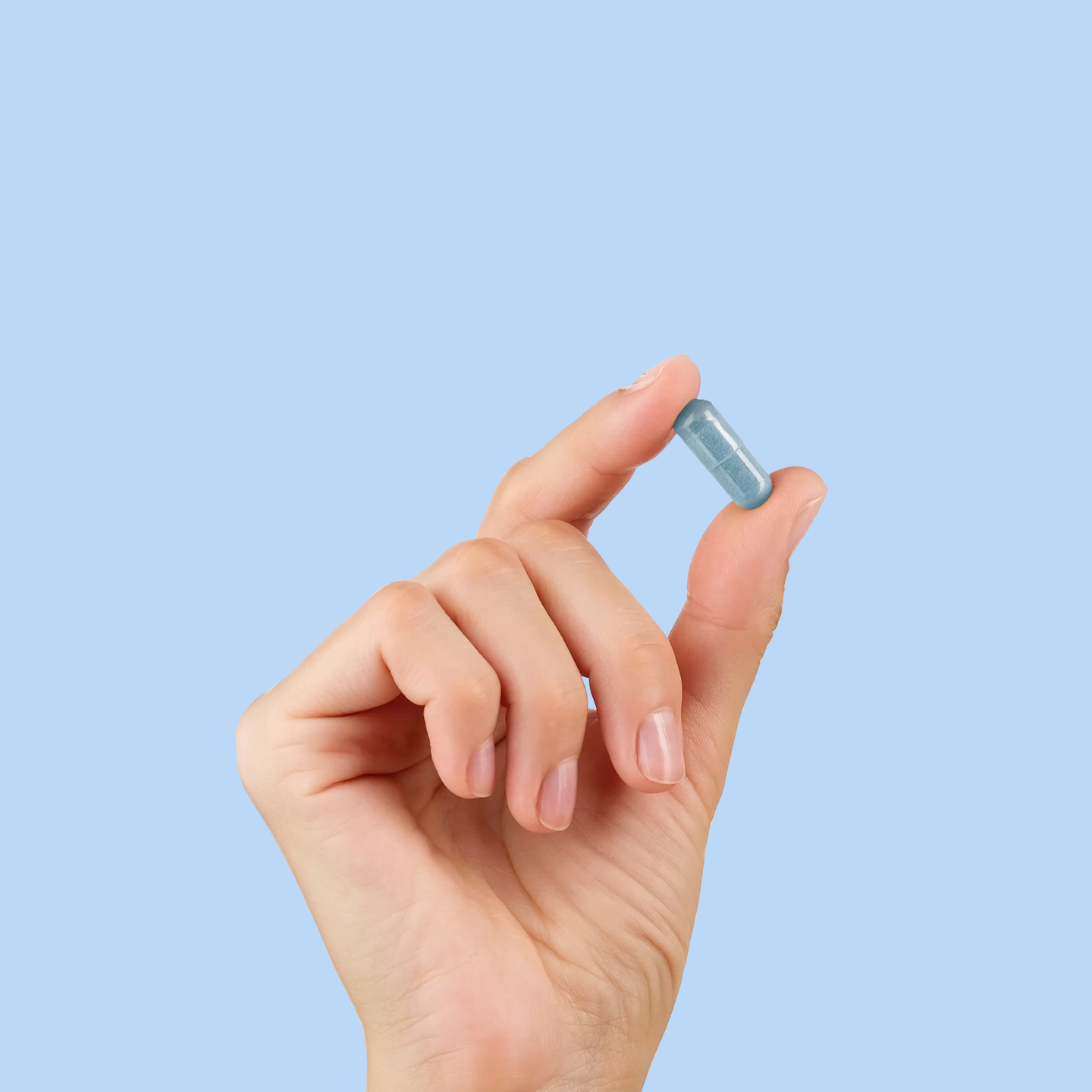 Hand holding methylene blue tablet between two fingers