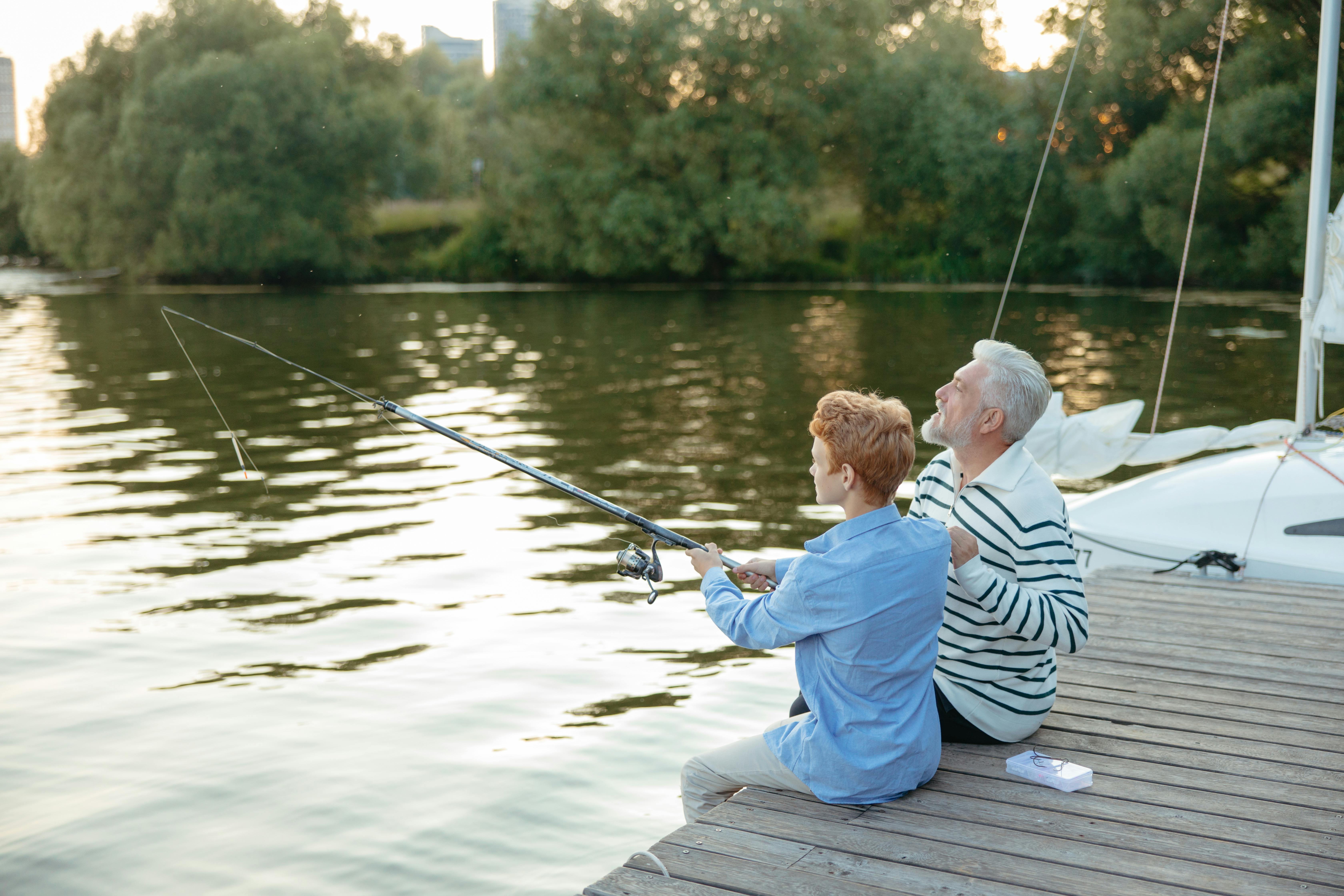 Older man teaching young boy to fish