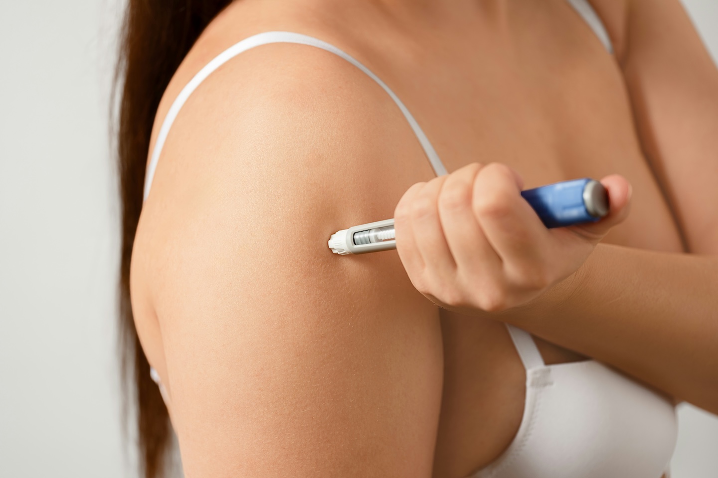 Person injecting semaglutide or tirzepatide into upper arm
