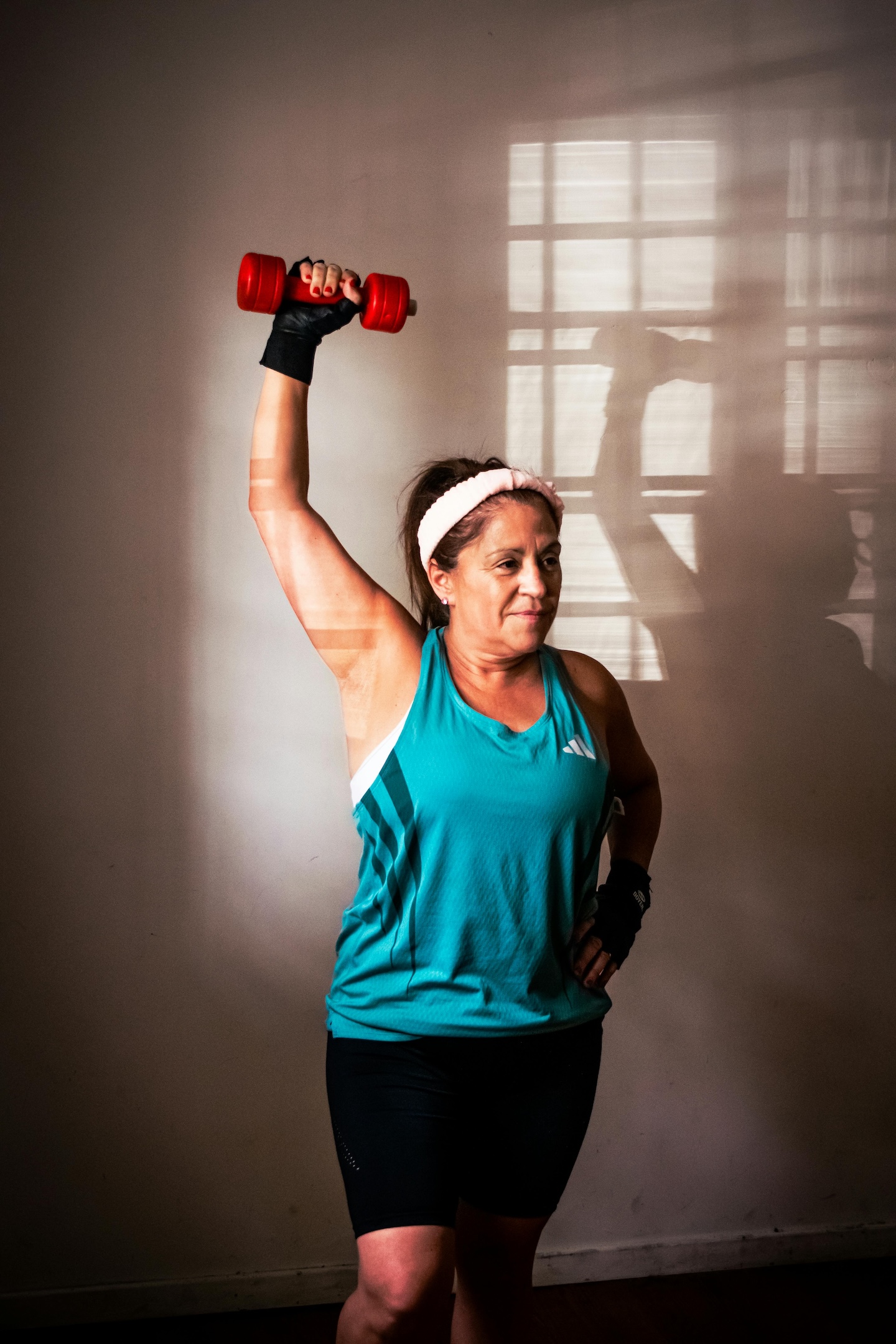 Middle age woman lifting dumbbell in home gym