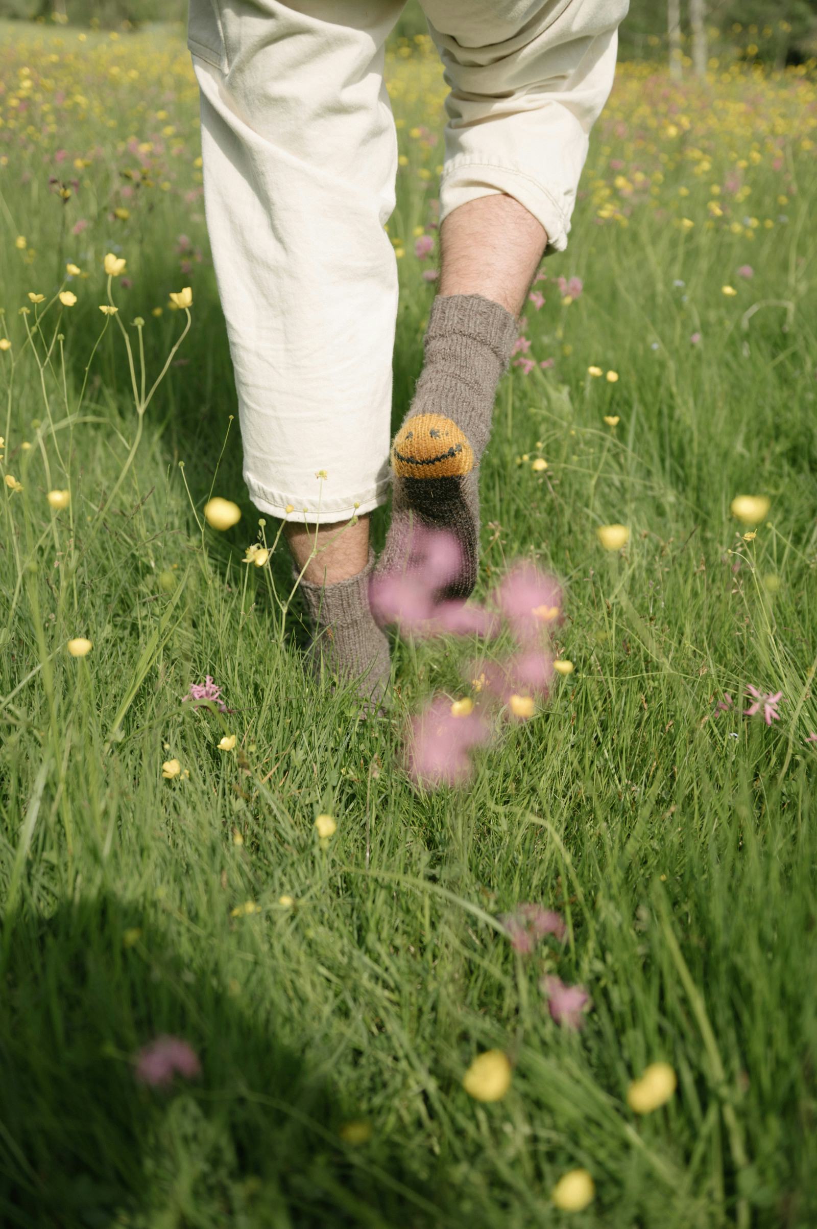 Person wearing socks walking through field of wildflowers