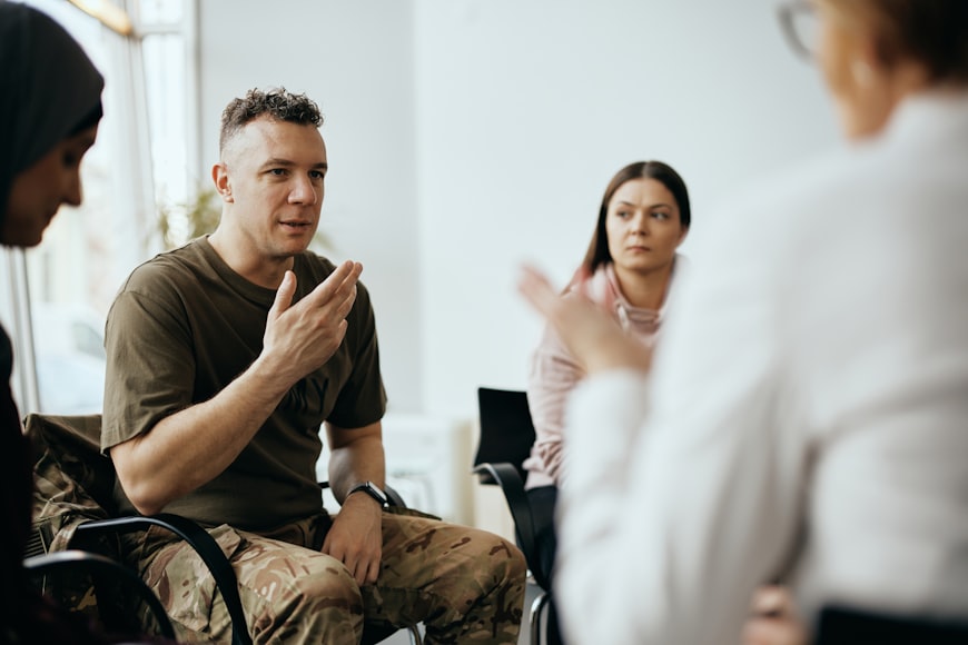 Multiple veterans sit in a circle for a group therapy session.