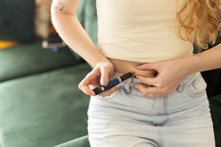 Someone pinches the skin on their abdomen to inject a weight-loss medication, such as tirzepatide or semaglutide.