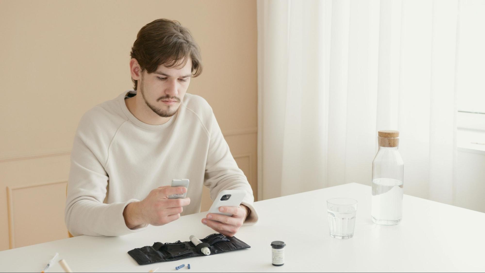 A young man checking his medication information on his phone at home.