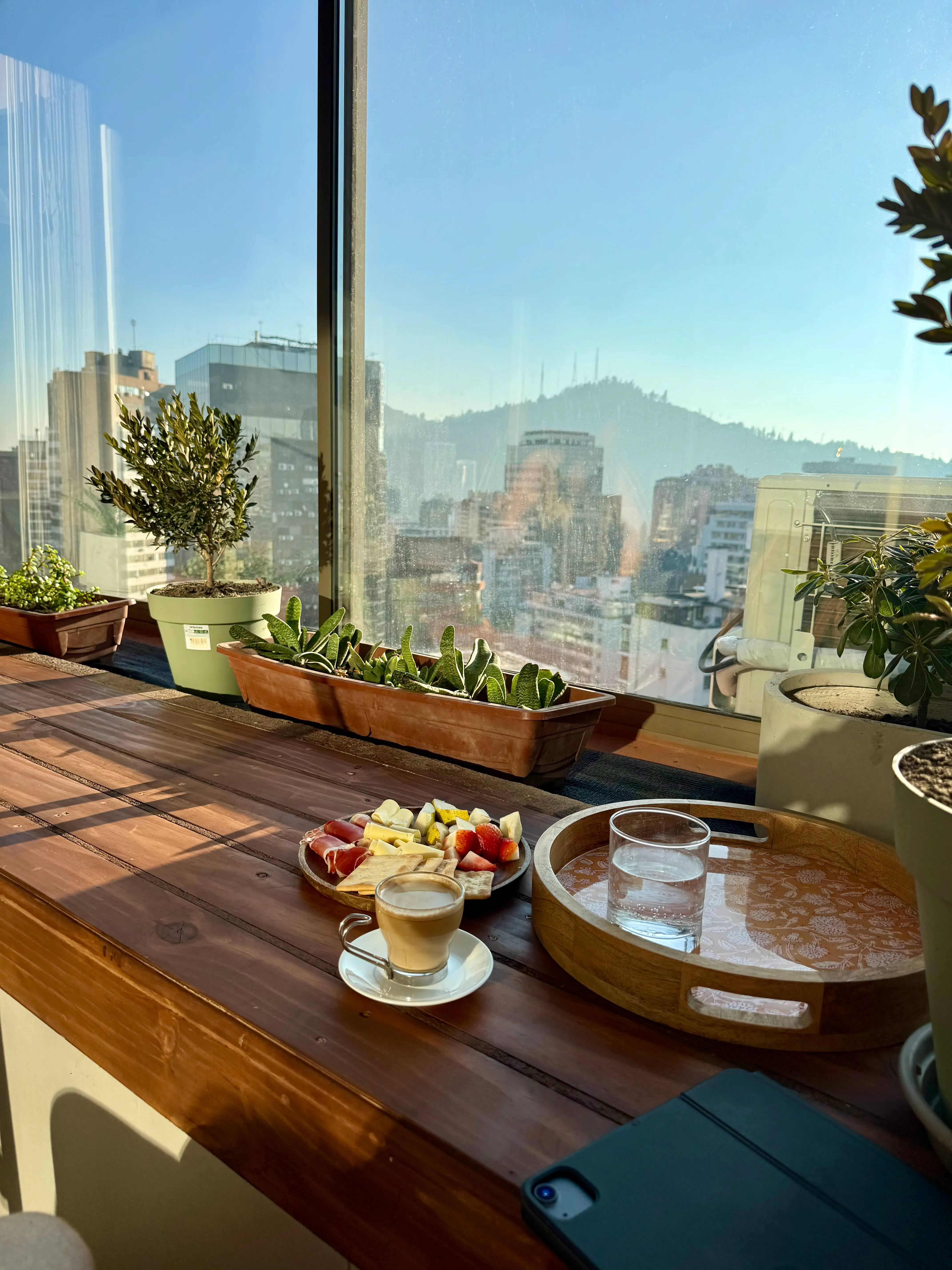 Sunroom workspace at Suite152 with coffee, iPad, and panoramic Santiago light — perfect for remote workers and extended stays