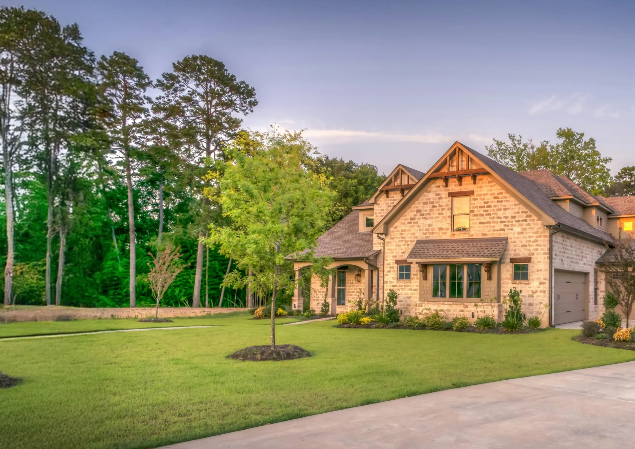 Newly installed lawn and young trees surrounding a brick home