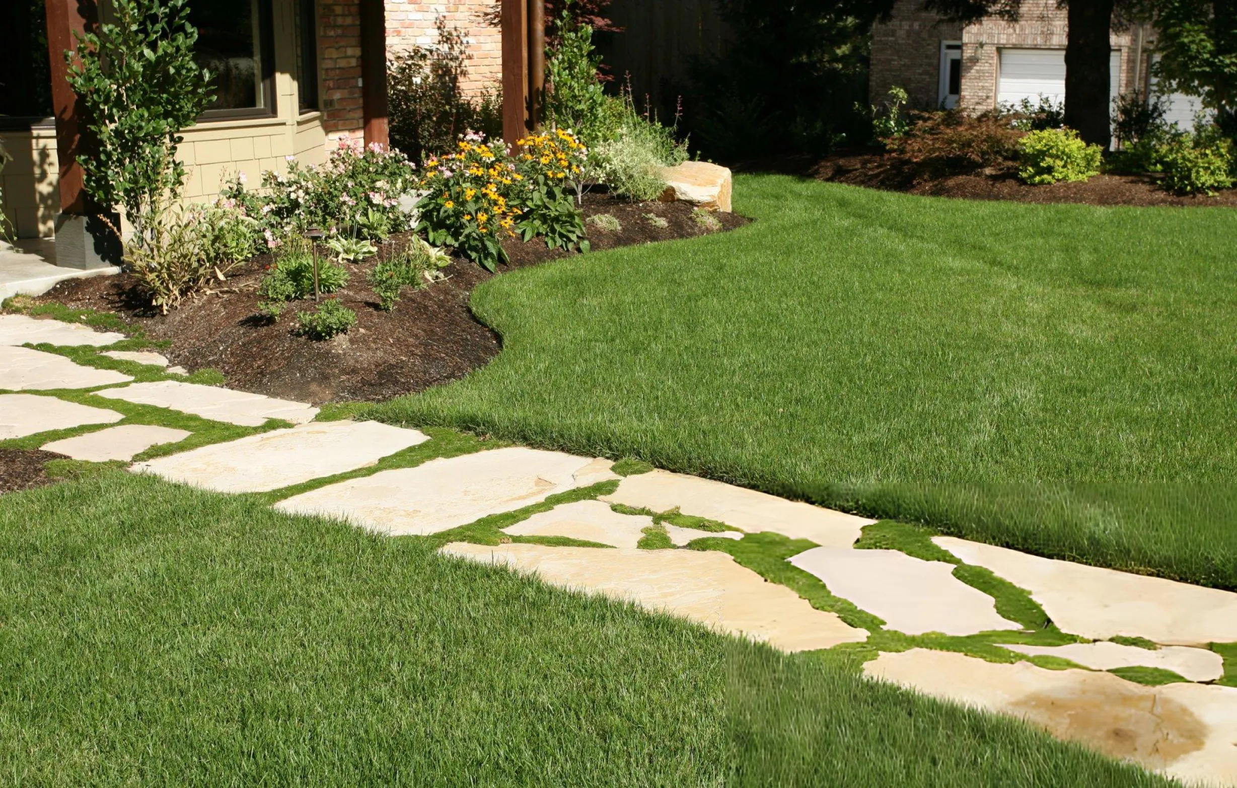 Landscaped front yard with a curved flower bed and natural stone walkway