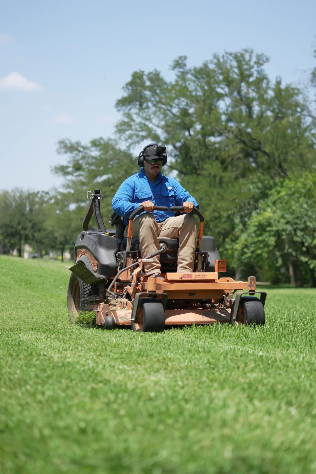 Landscaping crew member mowing a residential lawn