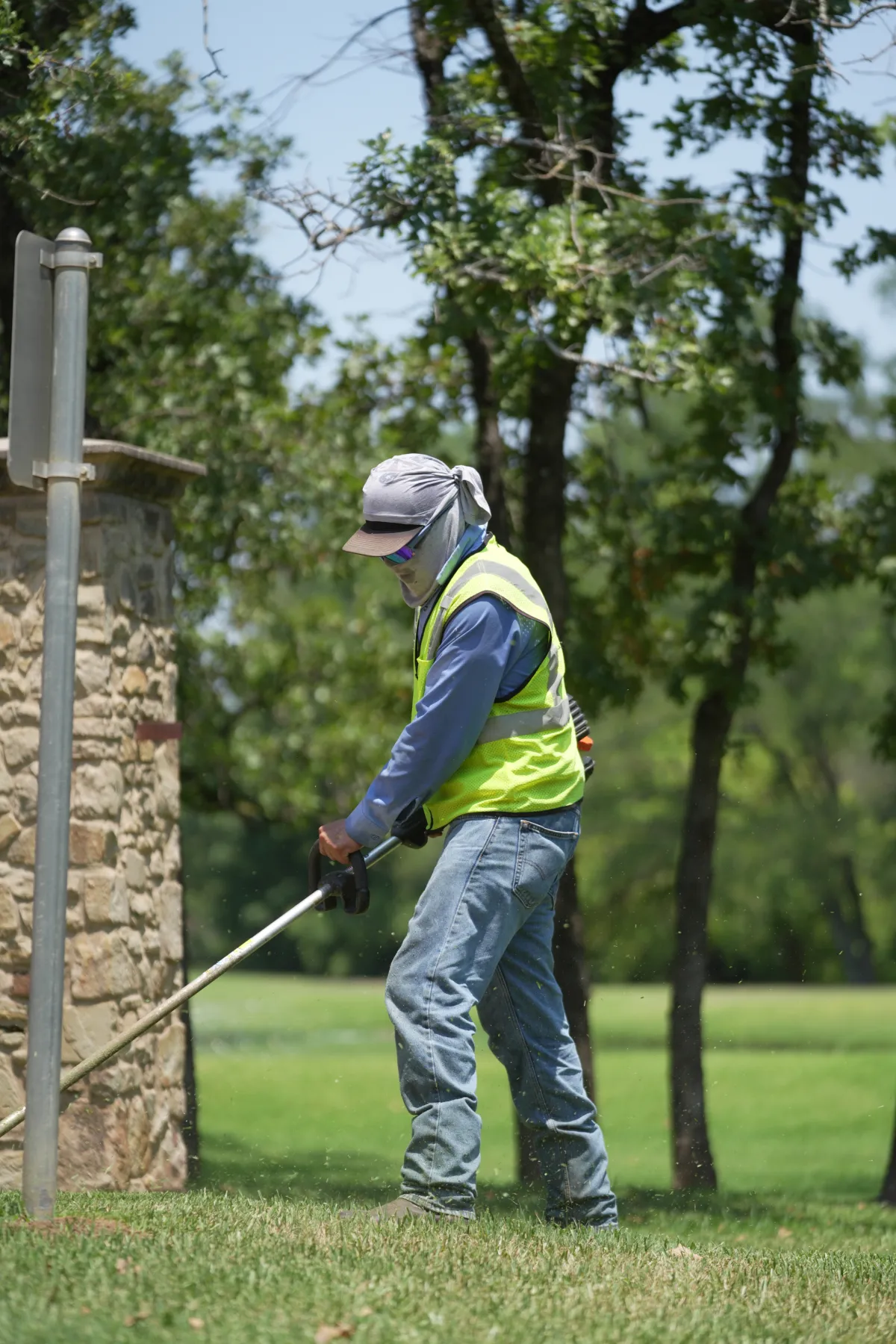 Landscaping crew member edging grass along a stone wall