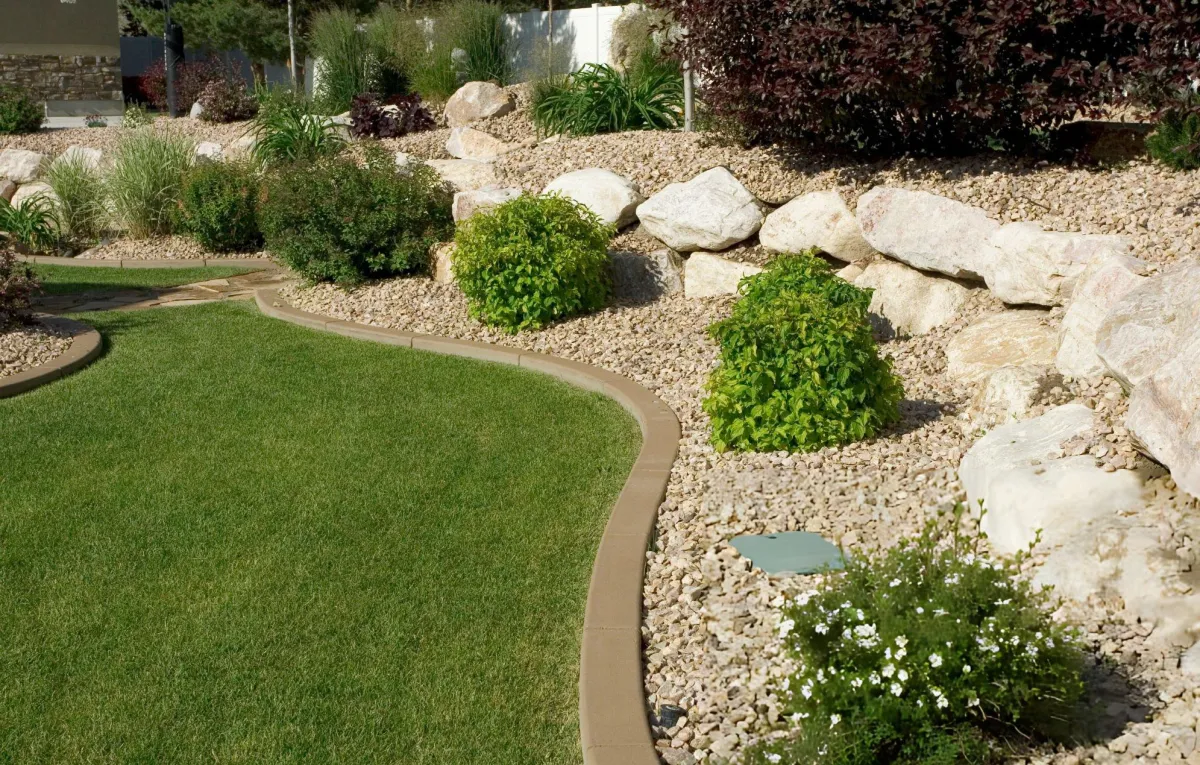 Landscaped garden bed with decorative rocks, shrubs, and lawn
