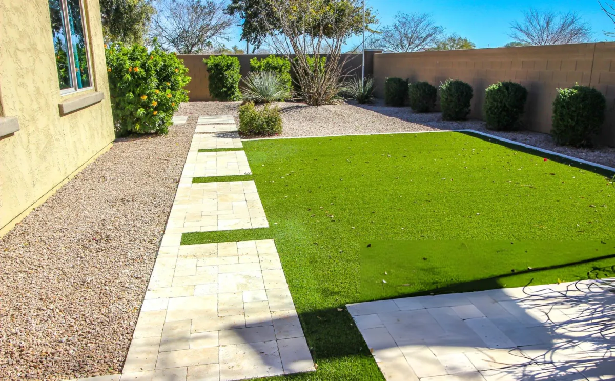 Landscaped backyard with a stone walkway and green lawn