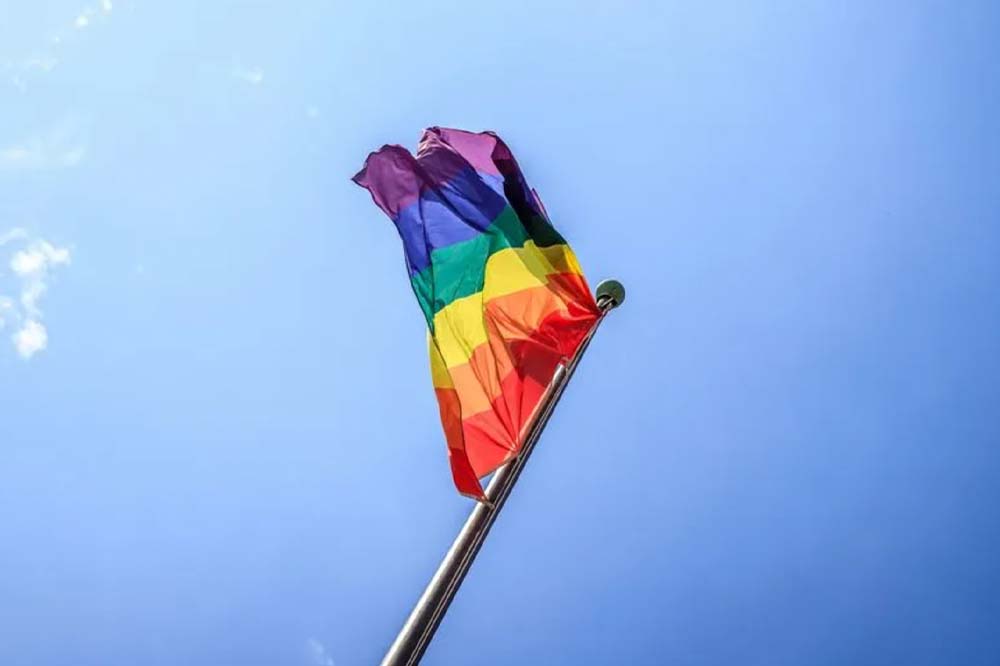Rainbow LGBTQ+ pride flag against a clear blue sky 