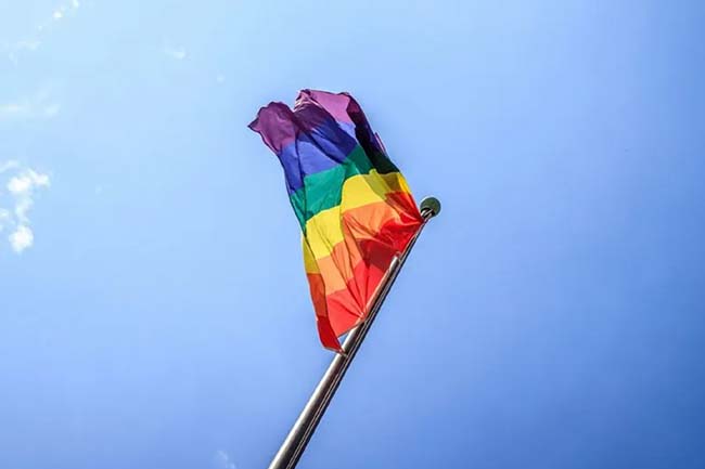 Rainbow LGBTQ+ pride flag against a clear blue sky 