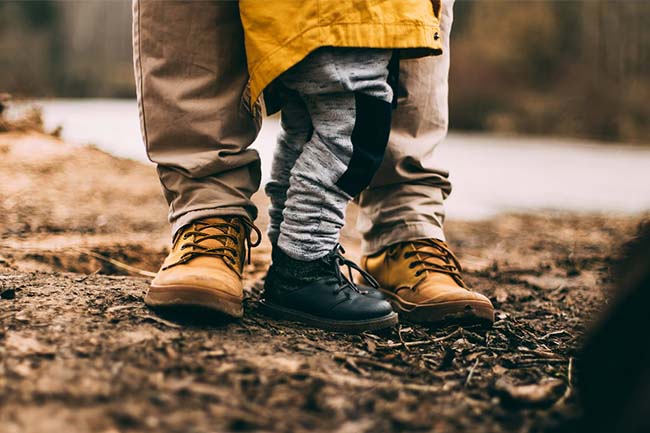 Close up of a child's small feet standing with their parent