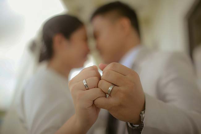 Arecently married couple holding hands with focus on their wedding rings