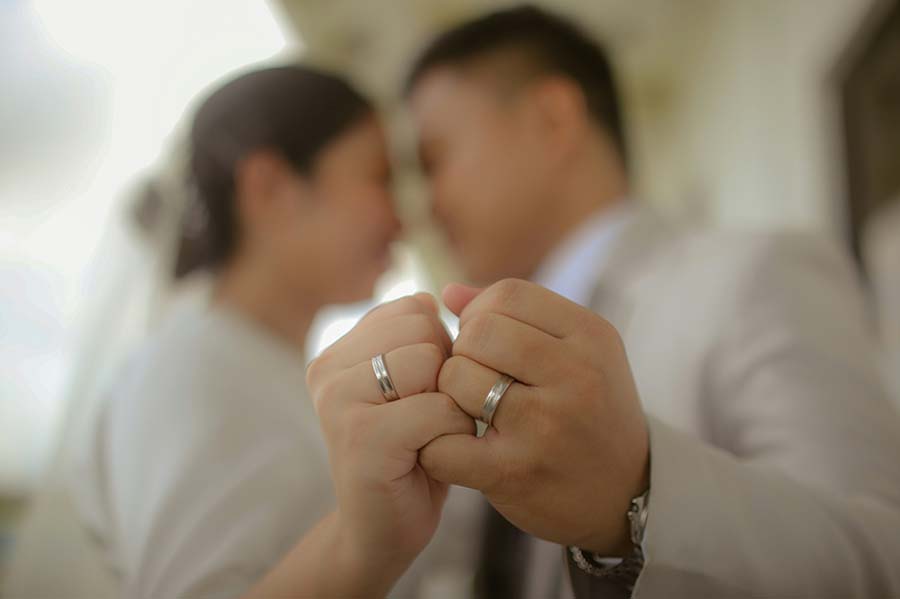 A recently married couple holding hands with focus on their wedding rings