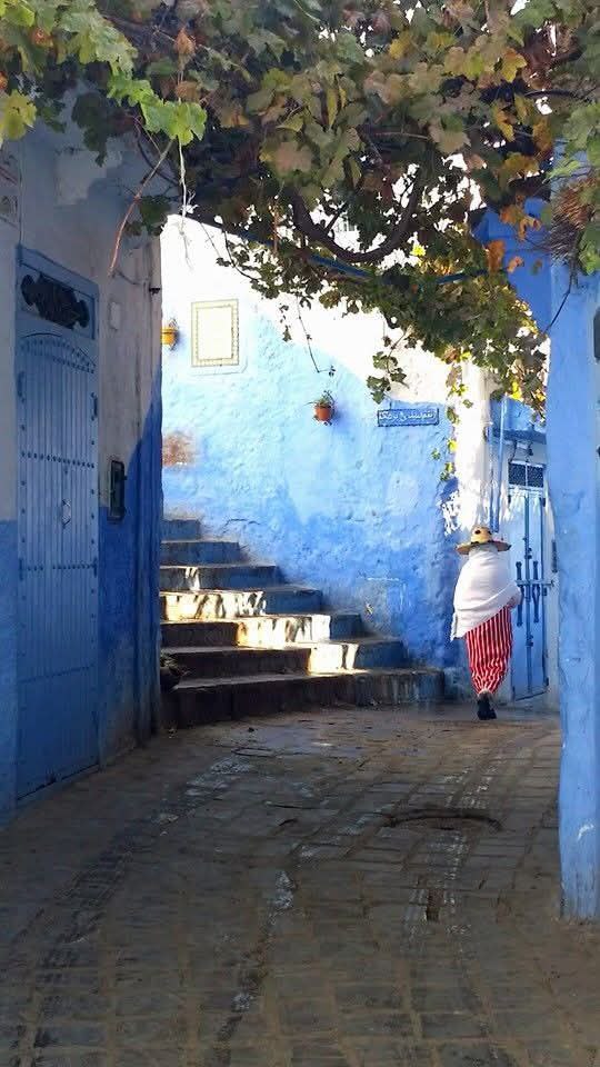 A woman in traditional clothing walks the streets of the Blue City. Chefchaoen, Morocco.