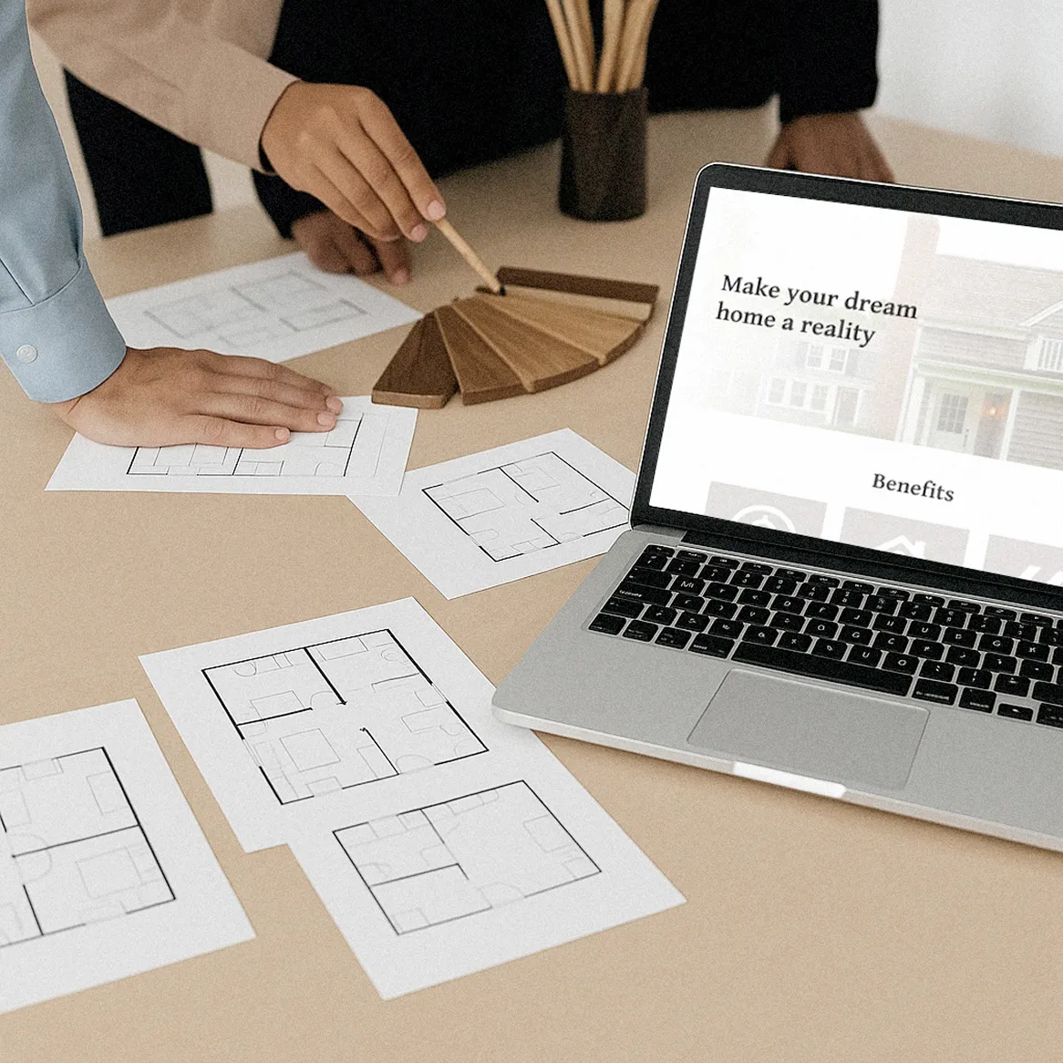 A laptop on a table where people discuss the details of an interior design project.