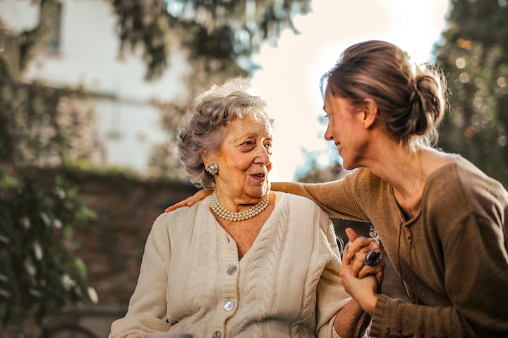 a woman and her elderly mother holding hands
