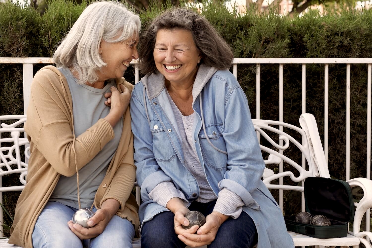 two women laughing and holding petanque balls