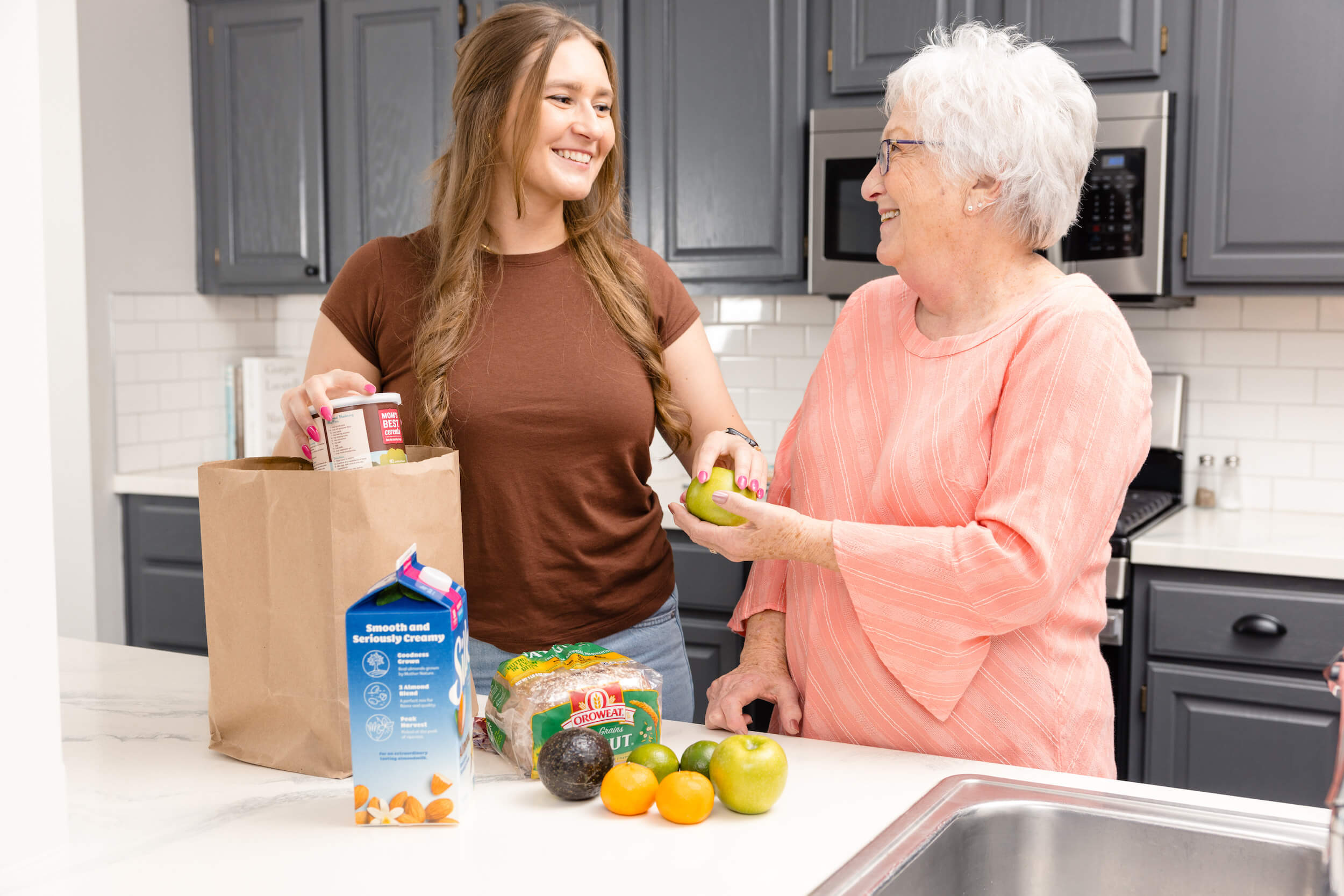 younger woman helping older woman with groceries