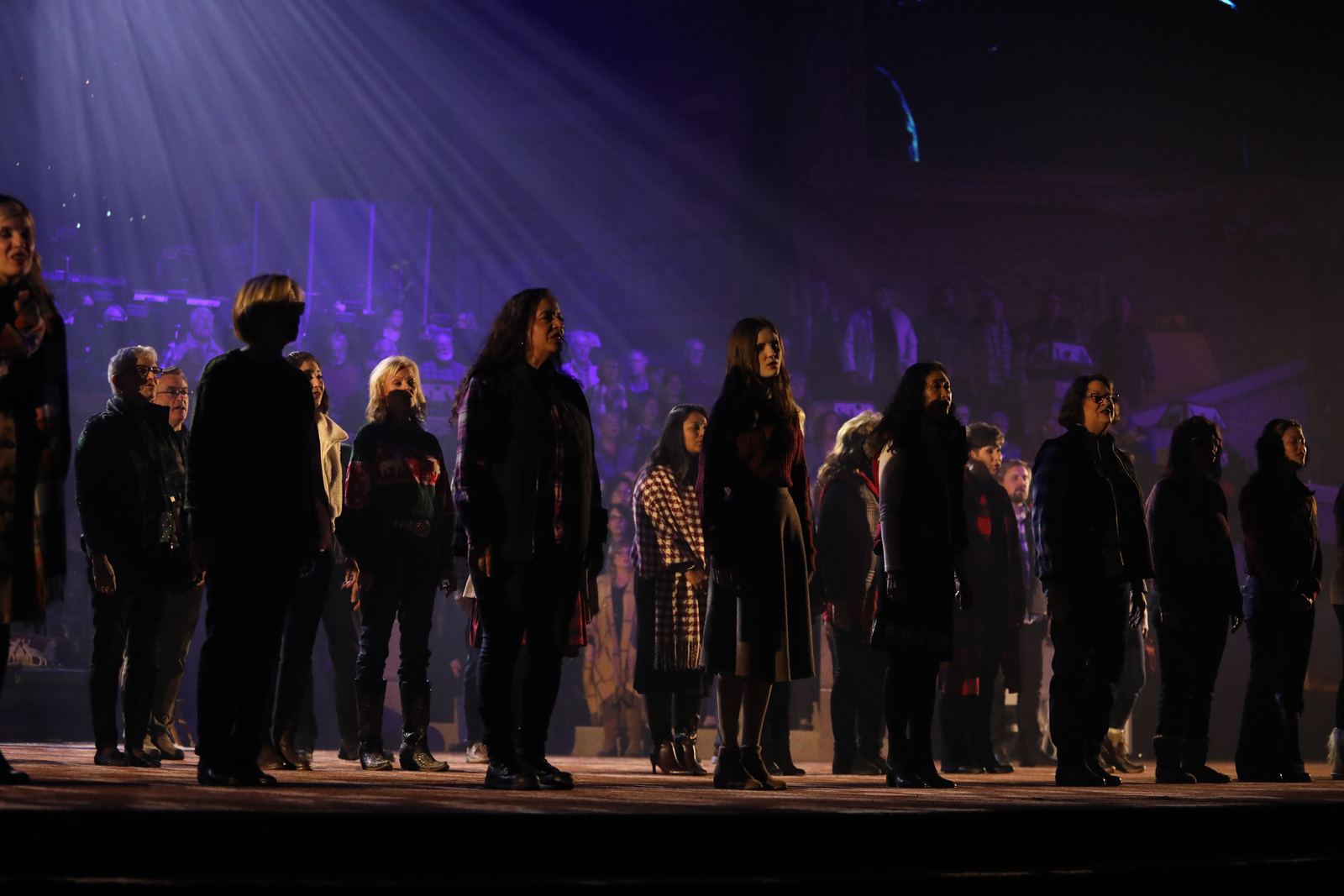 Adult choir on stage under purple light