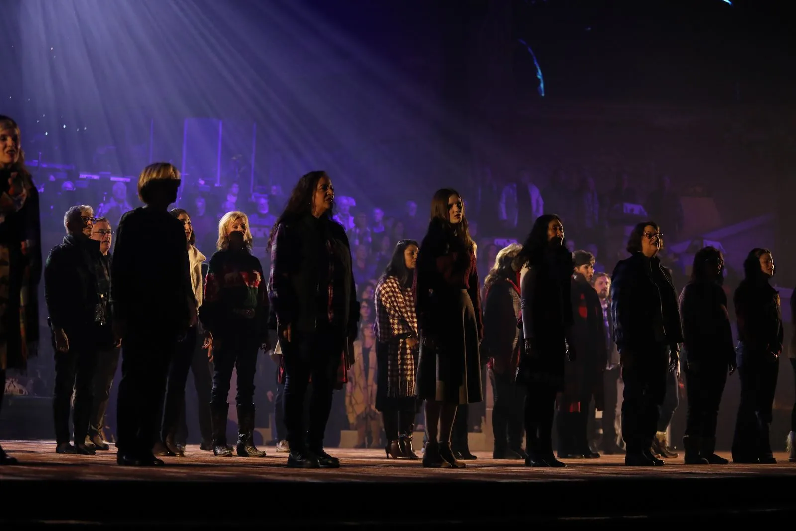 Adult choir on stage under purple light